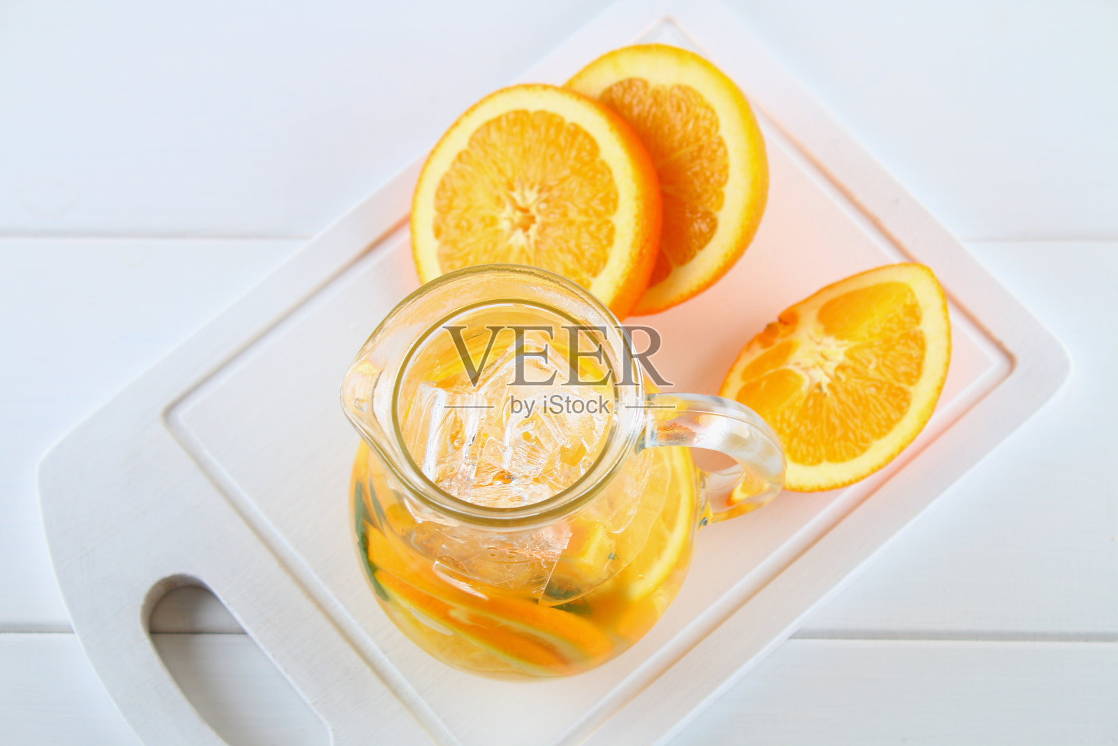 白色木桌上的水壶里装着橙色的排毒水。健康食品,饮料。照片摄影图片