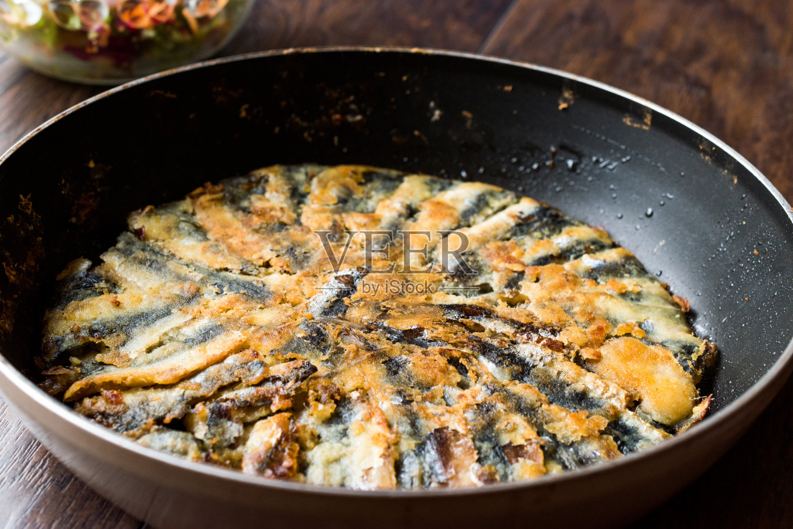新鲜炸沙丁鱼平底锅与沙拉在木表面。照片摄影图片