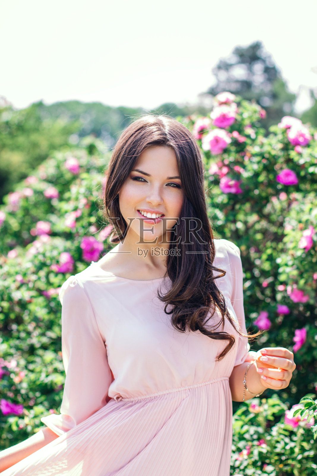 户外时尚照片美丽的年轻幸福微笑的女人被鲜花包围。春天开花照片摄影图片