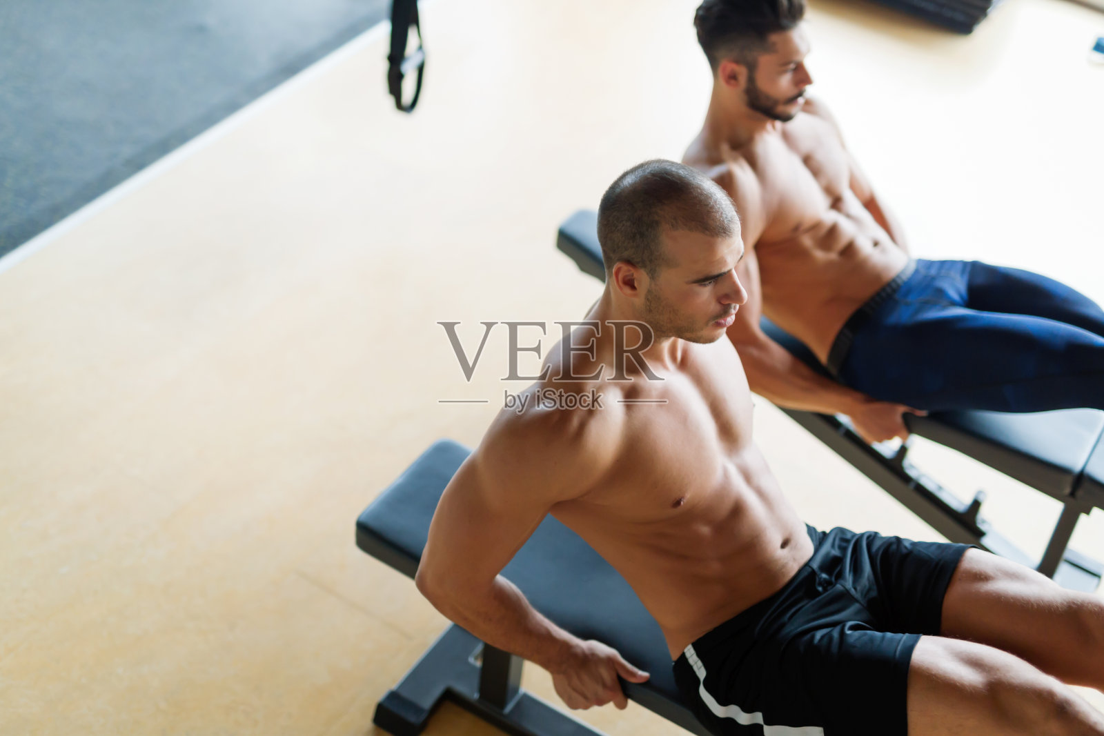 强壮的男人在长凳上做腹肌仰卧起坐照片摄影图片