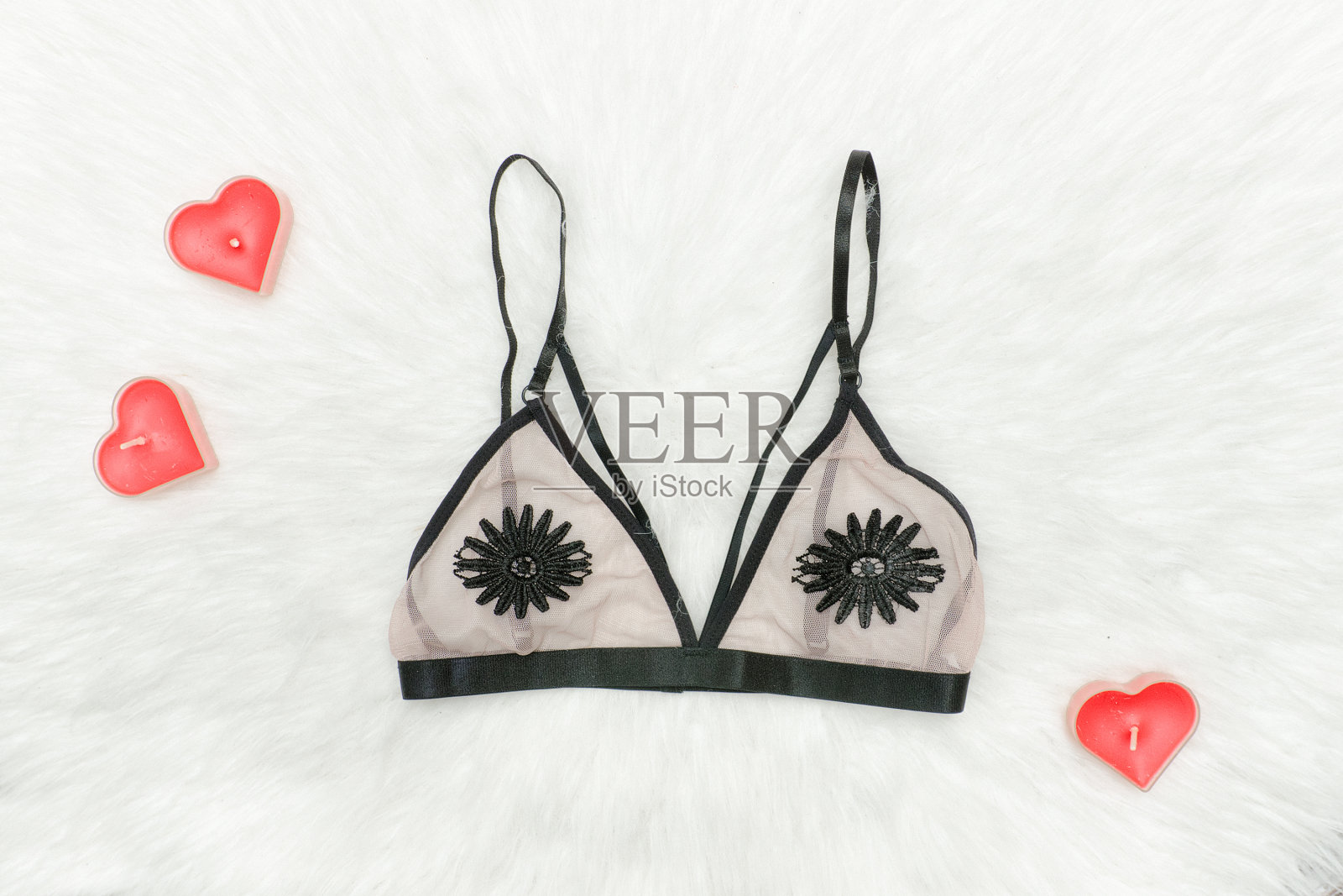 带花的米色胸罩。白色的皮毛,红色的心形蜡烛。时尚的概念照片摄影图片