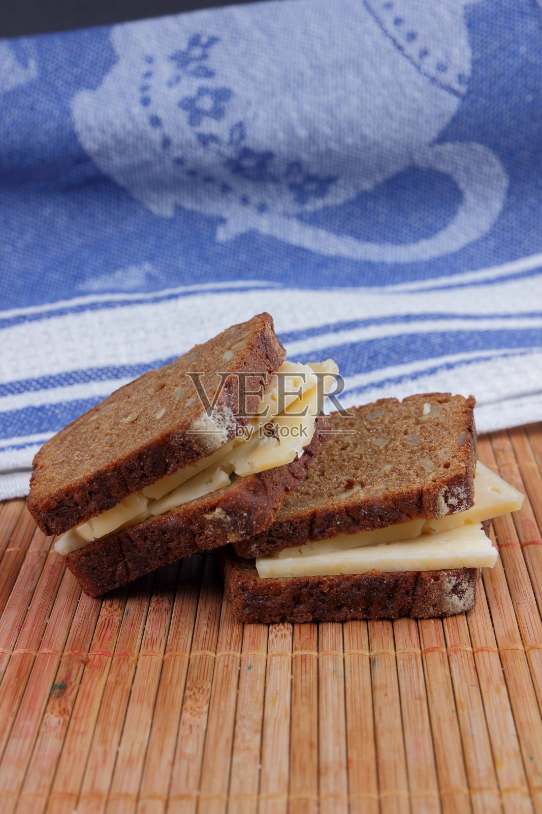 黑面包配硬奶酪,蓝色餐巾,黑面包配谷物,简单的食物,碎奶酪竹制背景,复古风格照片摄影图片