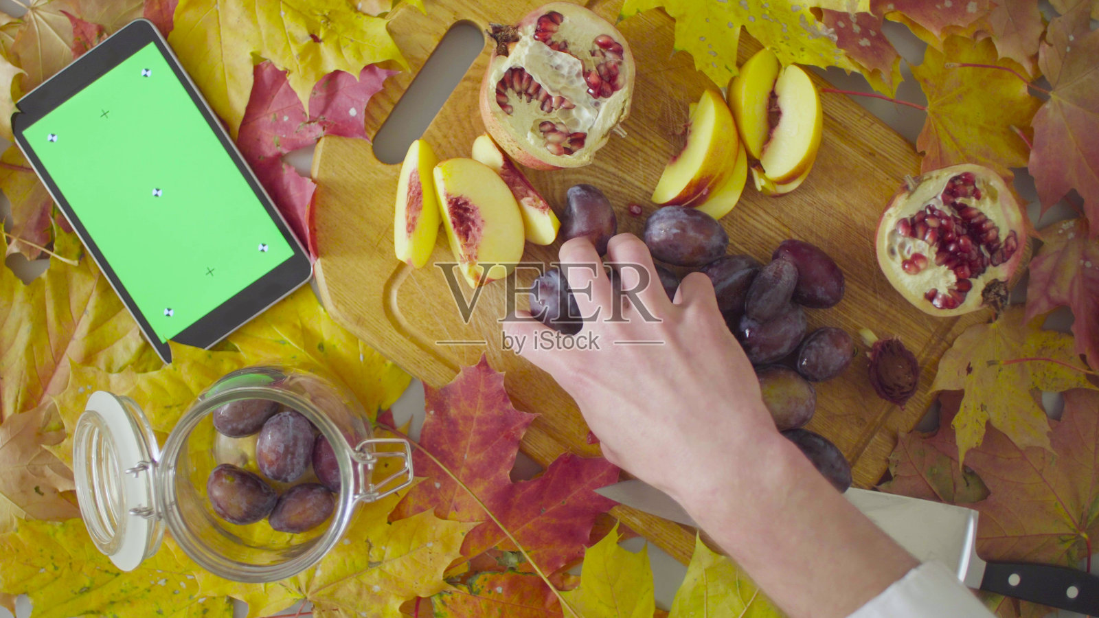 秋天的静物画。厨师把李子放进罐子里照片摄影图片