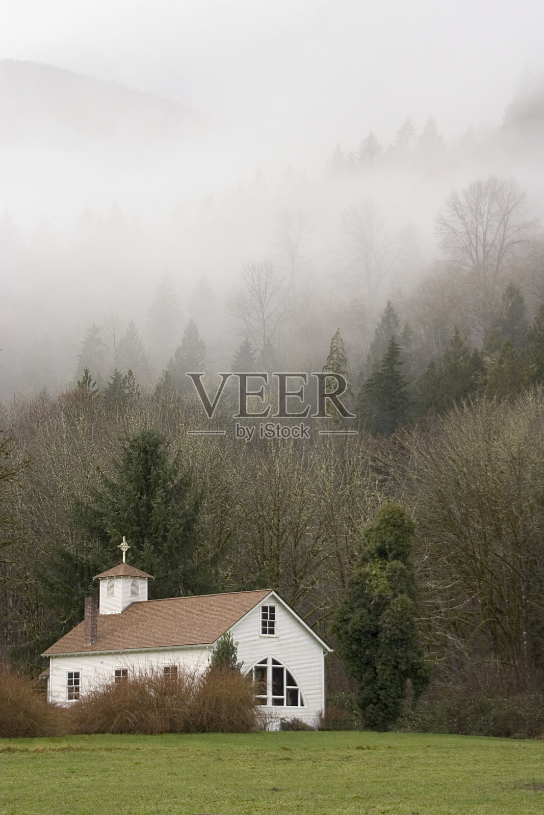 雾蒙蒙山坡上的乡村小教堂照片摄影图片