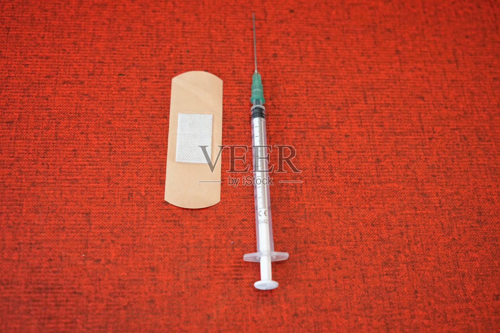 红色背景上有注射器和石膏。有选择性的重点照片摄影图片