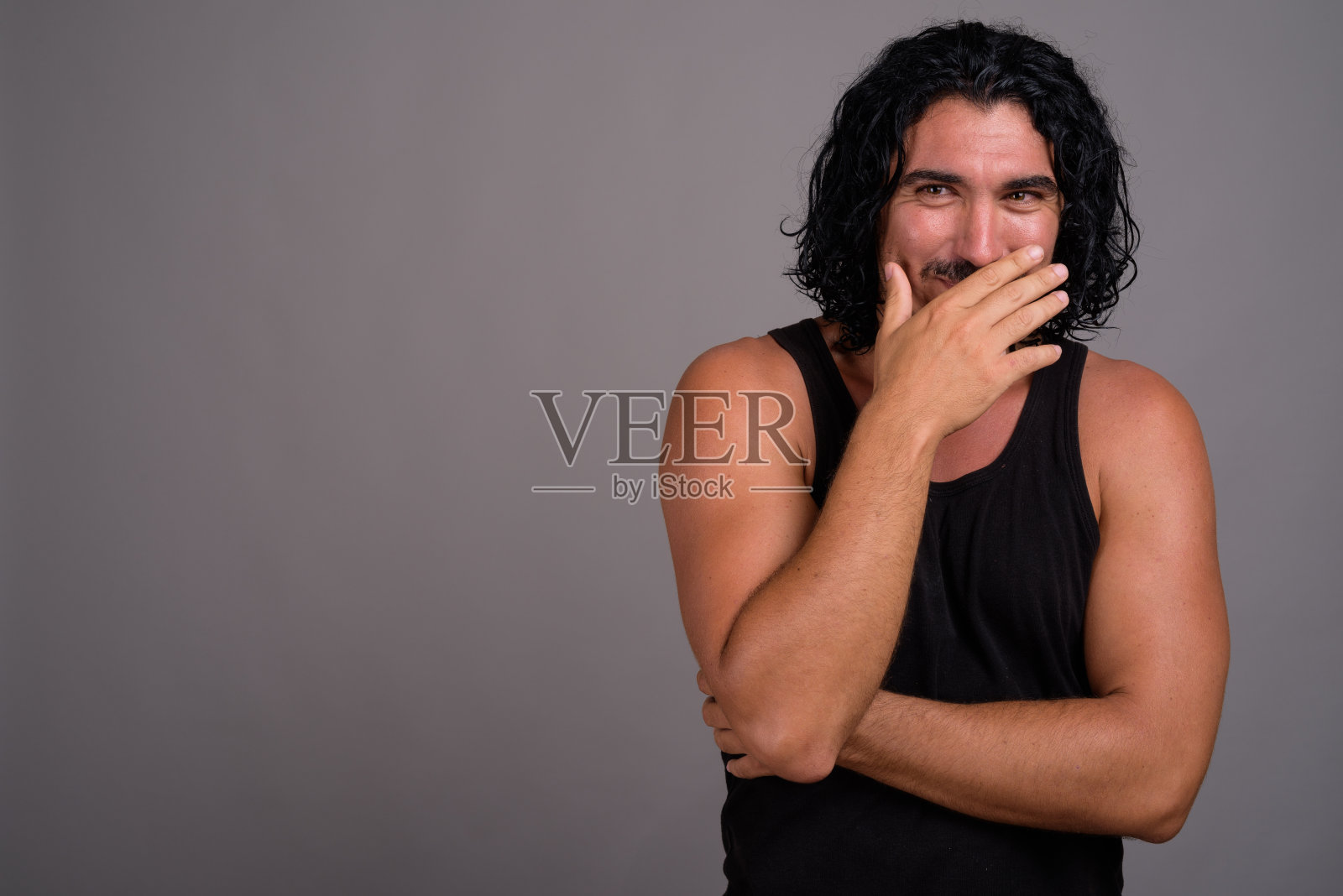 工作室拍摄的年轻英俊的男子与胡子穿背心对灰色背景照片摄影图片