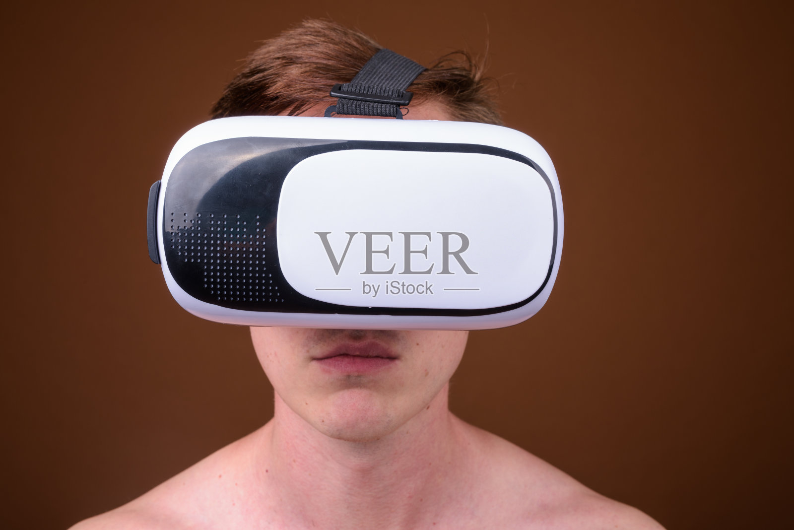 工作室拍摄的年轻英俊的男子赤膊而使用虚拟现实耳机对彩色背景照片摄影图片