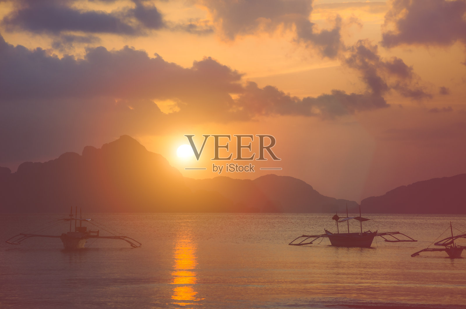 菲律宾巴拉望岛爱妮岛的日落,停泊在海湾的螃蟹船照片摄影图片