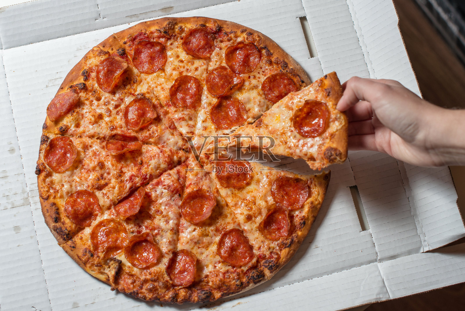 意大利腊肠和奶酪披萨。手里拿着一片披萨照片摄影图片