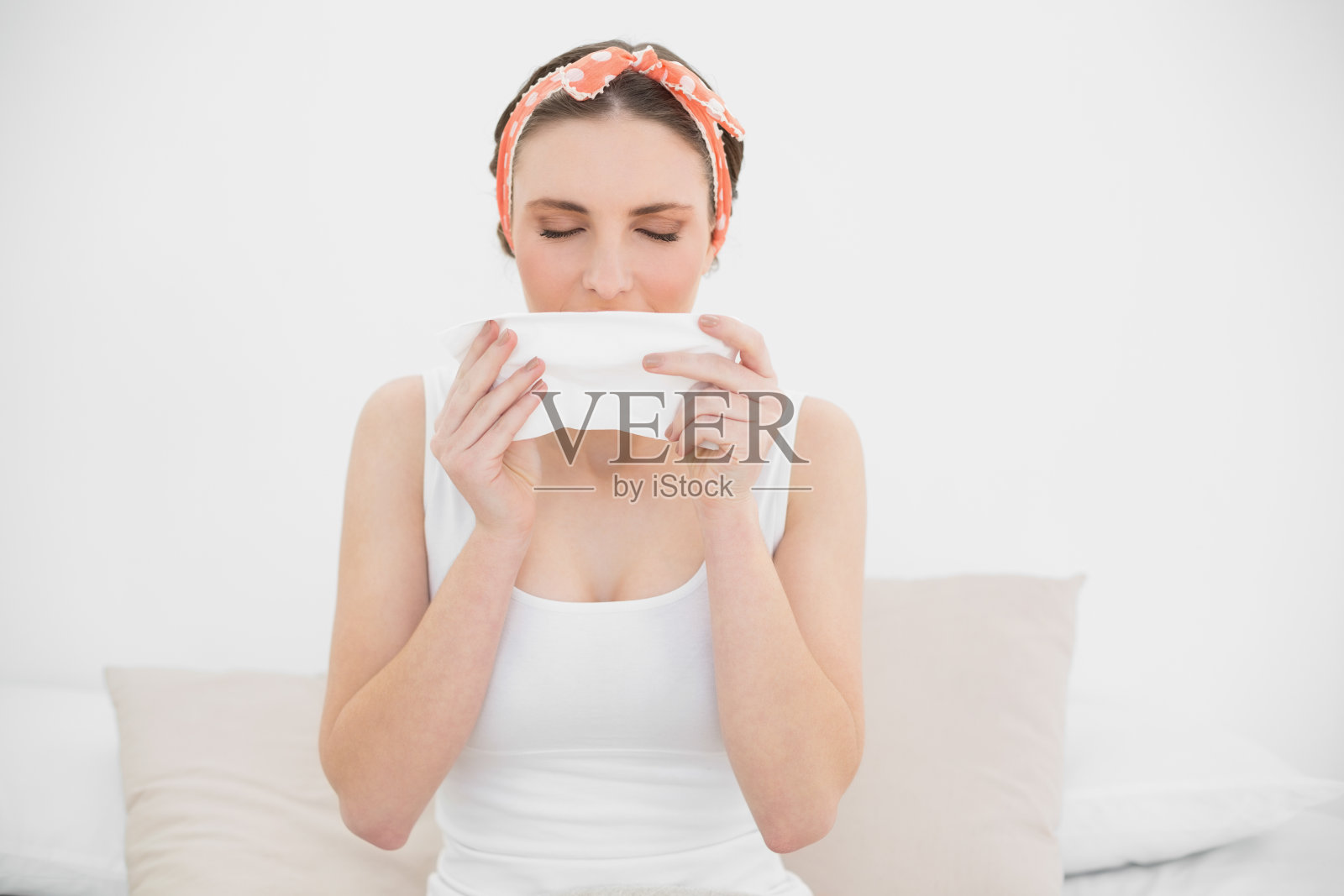 年轻女人对着手帕打喷嚏照片摄影图片