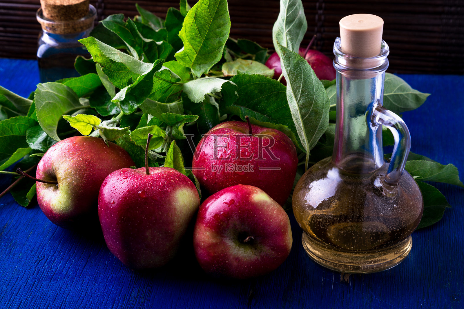 苹果醋。蓝色背景上的三个玻璃瓶。红苹果照片摄影图片