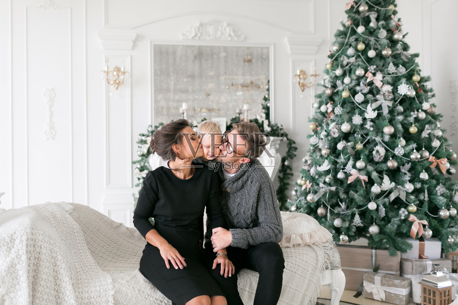 快乐的家庭在圣诞节的早晨在家里。背景上的圣诞树。新年快乐照片摄影图片