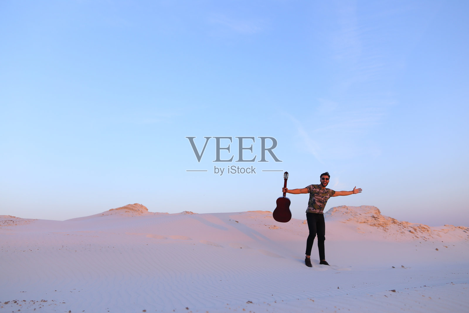 被沙漠美景所启发弹吉他的阿拉伯男子照片摄影图片