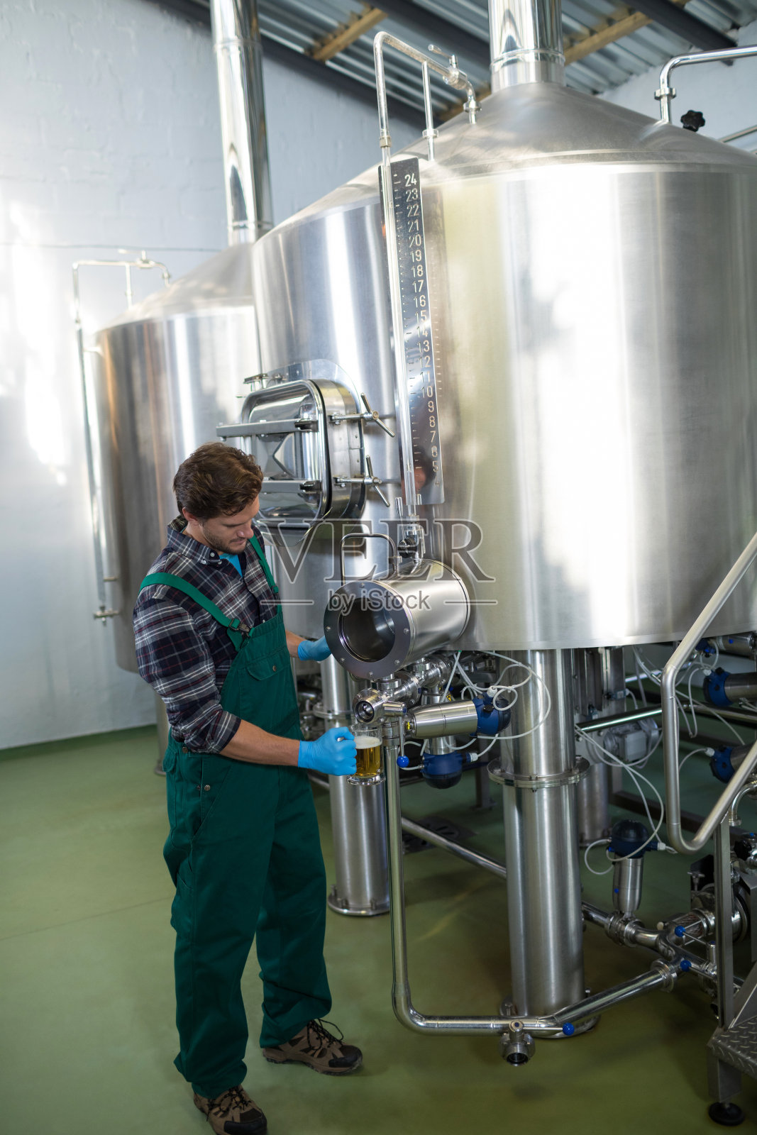 男工人从储罐中取出啤酒照片摄影图片