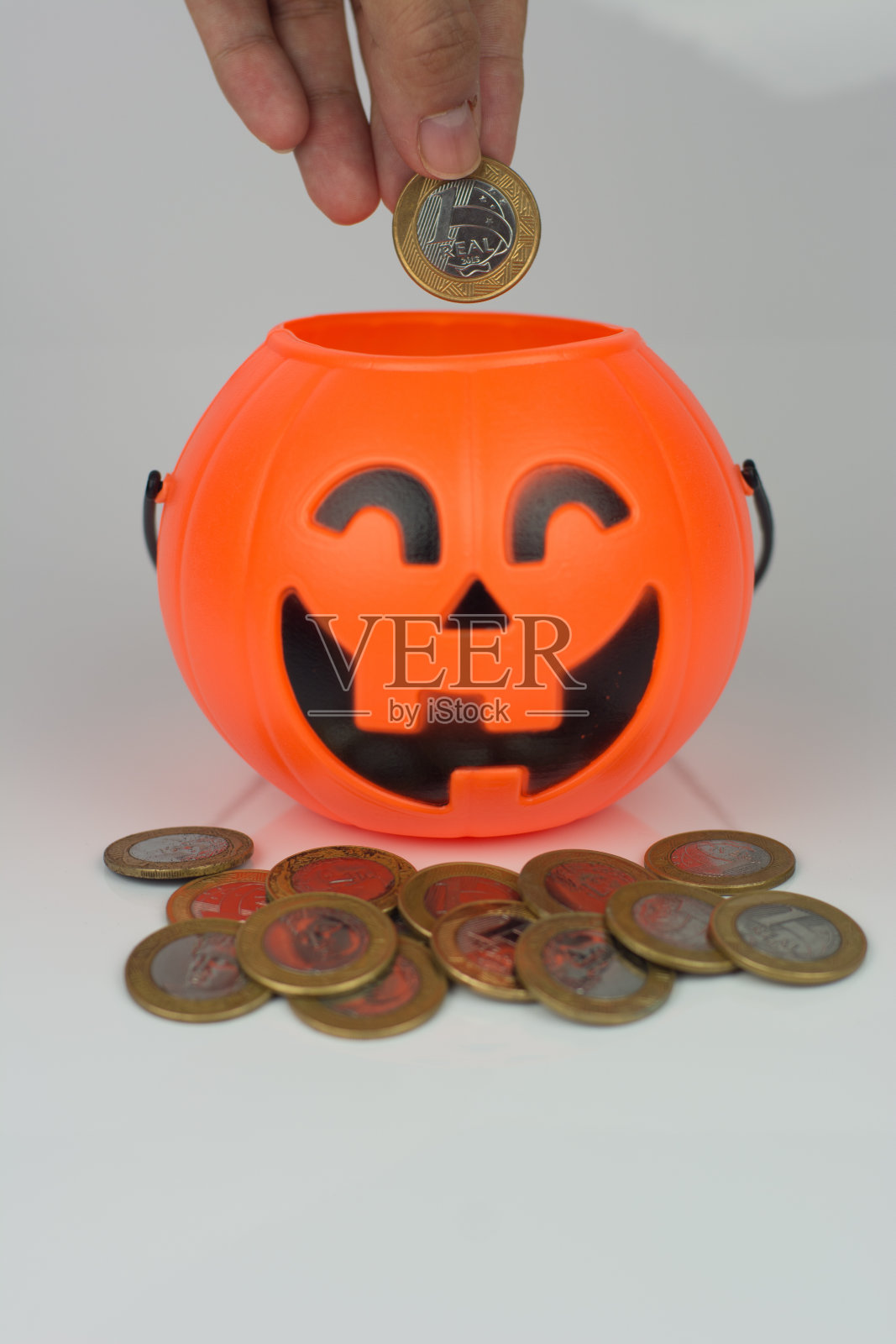 手把一枚硬币放进万圣节南瓜里照片摄影图片