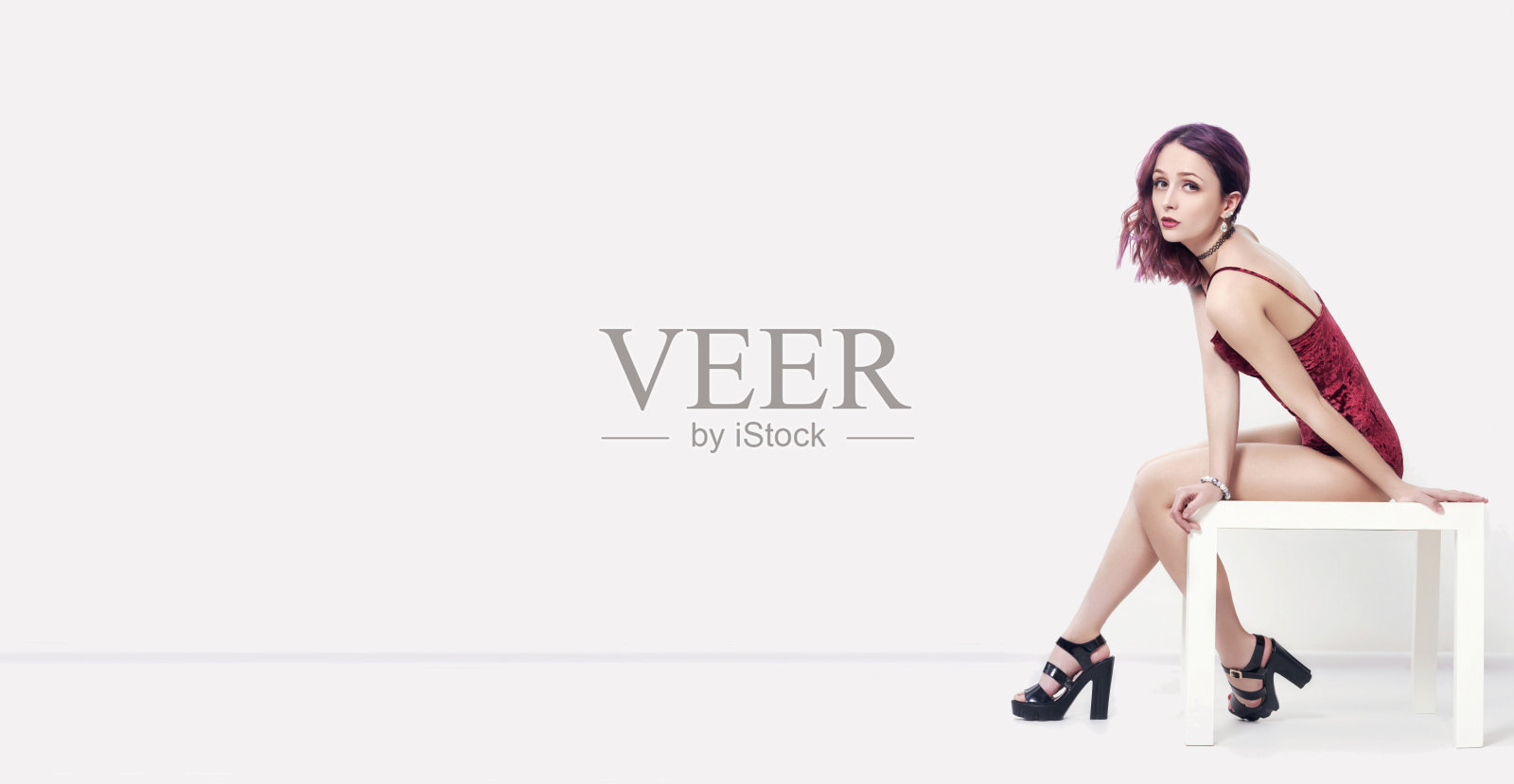 模型。性感的女人与紫色的头发在内衣坐在桌子和摆姿势。白底上的女人。时尚艺术肖像迷人的性感女孩照片摄影图片