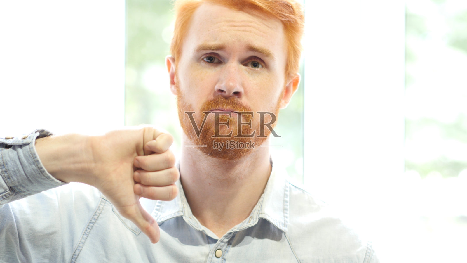 表现不佳,年轻人不满竖起拇指向下照片摄影图片