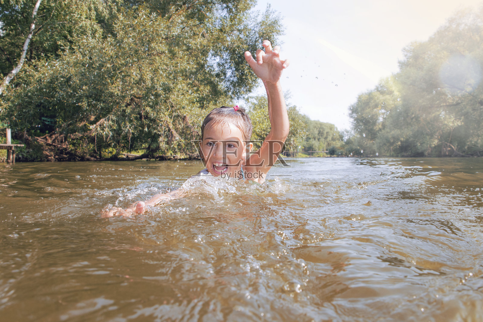 在河里游泳的孩子。女孩在河里游泳。照片摄影图片