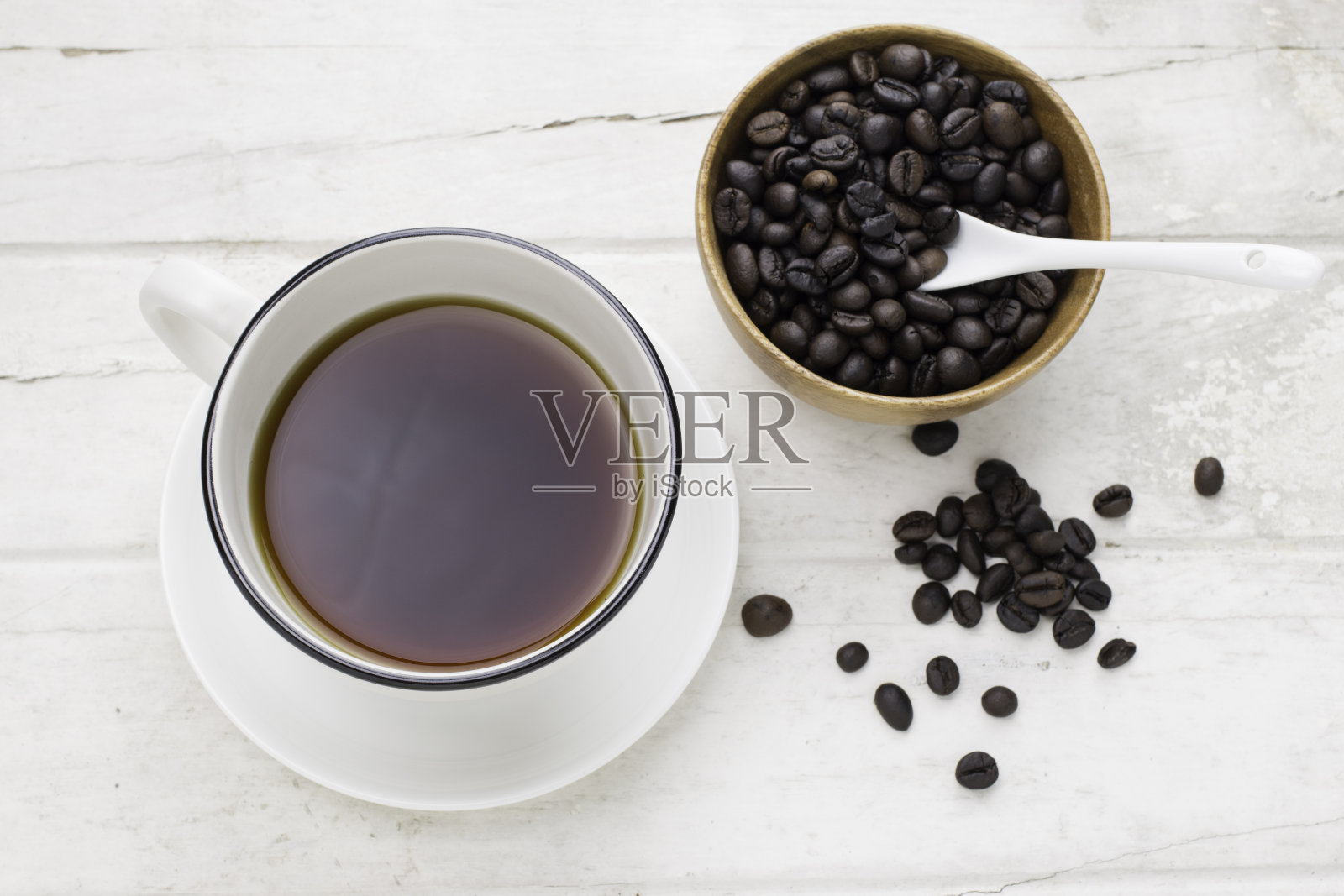 白杯子里装着黑咖啡,白桌子上放着咖啡豆和勺子。照片摄影图片
