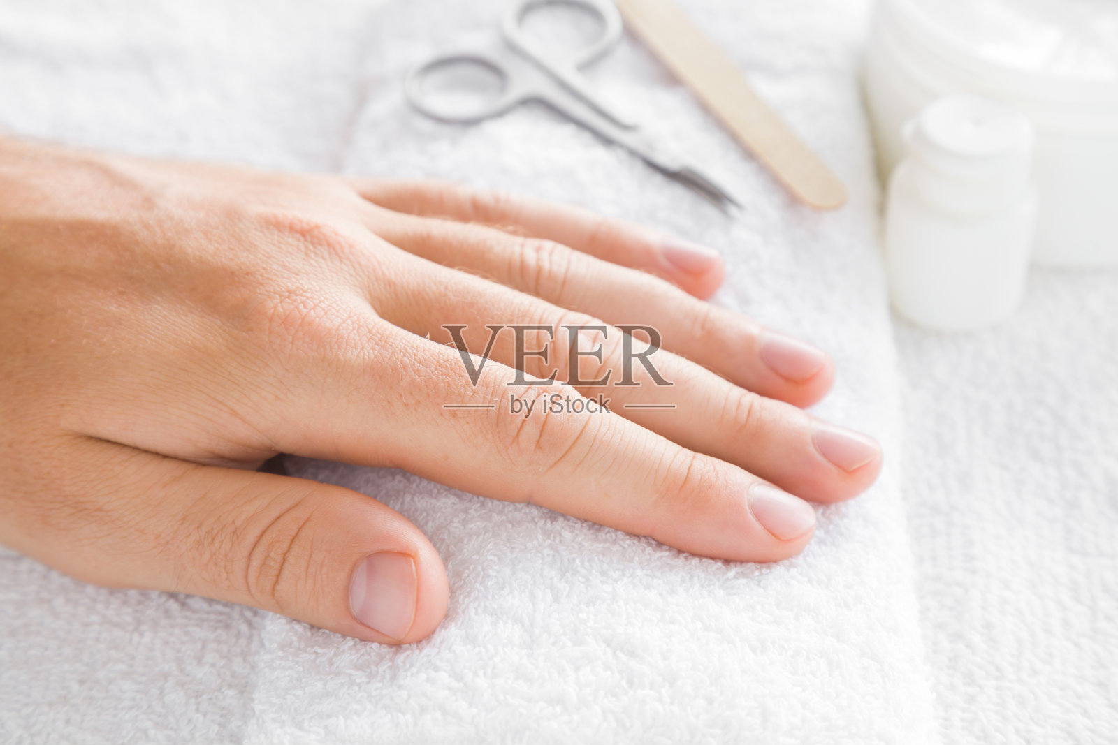 关心男人的指甲。修指甲美容院。剪刀和指甲锉放在白毛巾上。照片摄影图片