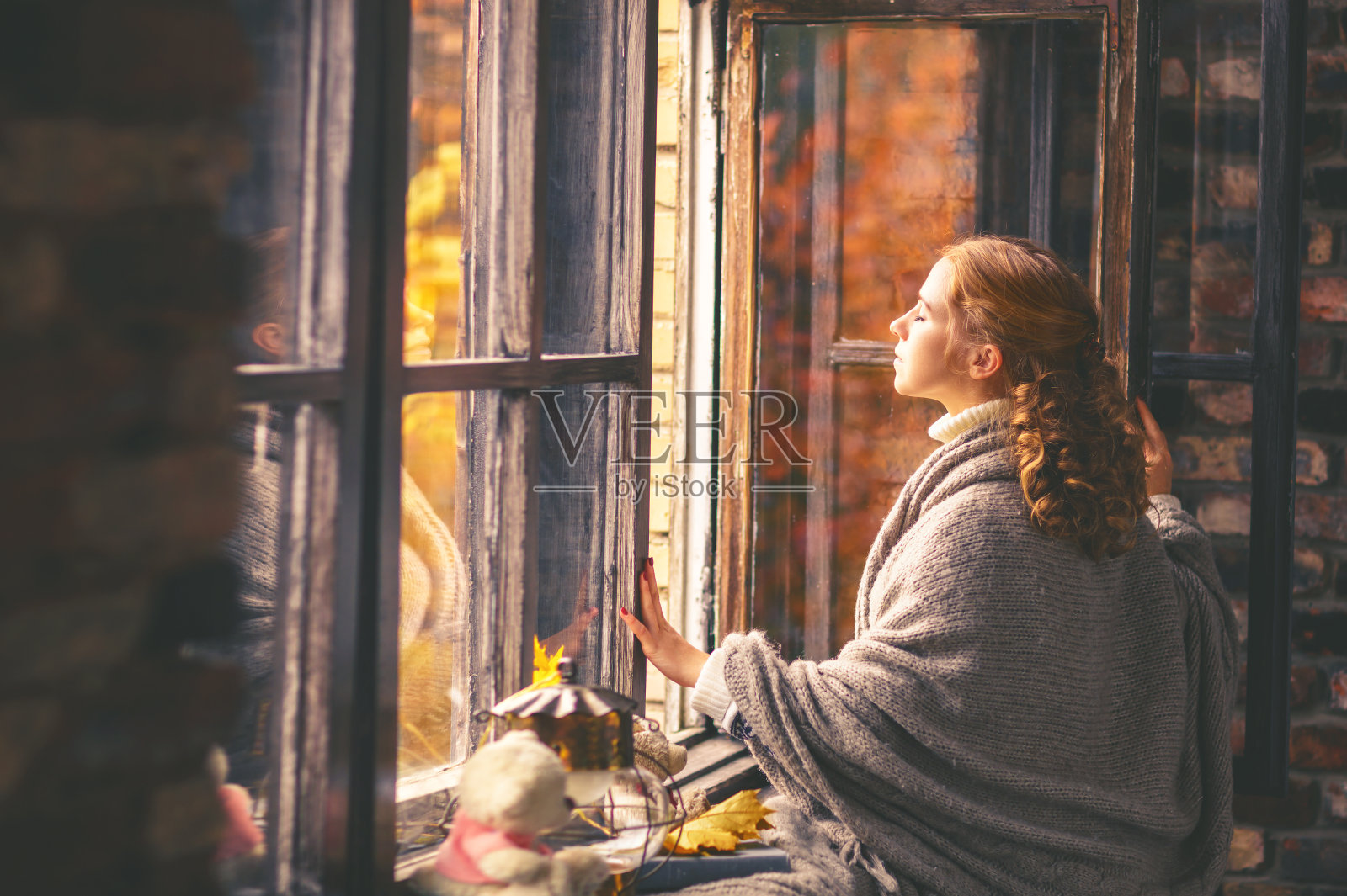 快乐的女人在敞开的窗口享受秋天的空气照片摄影图片