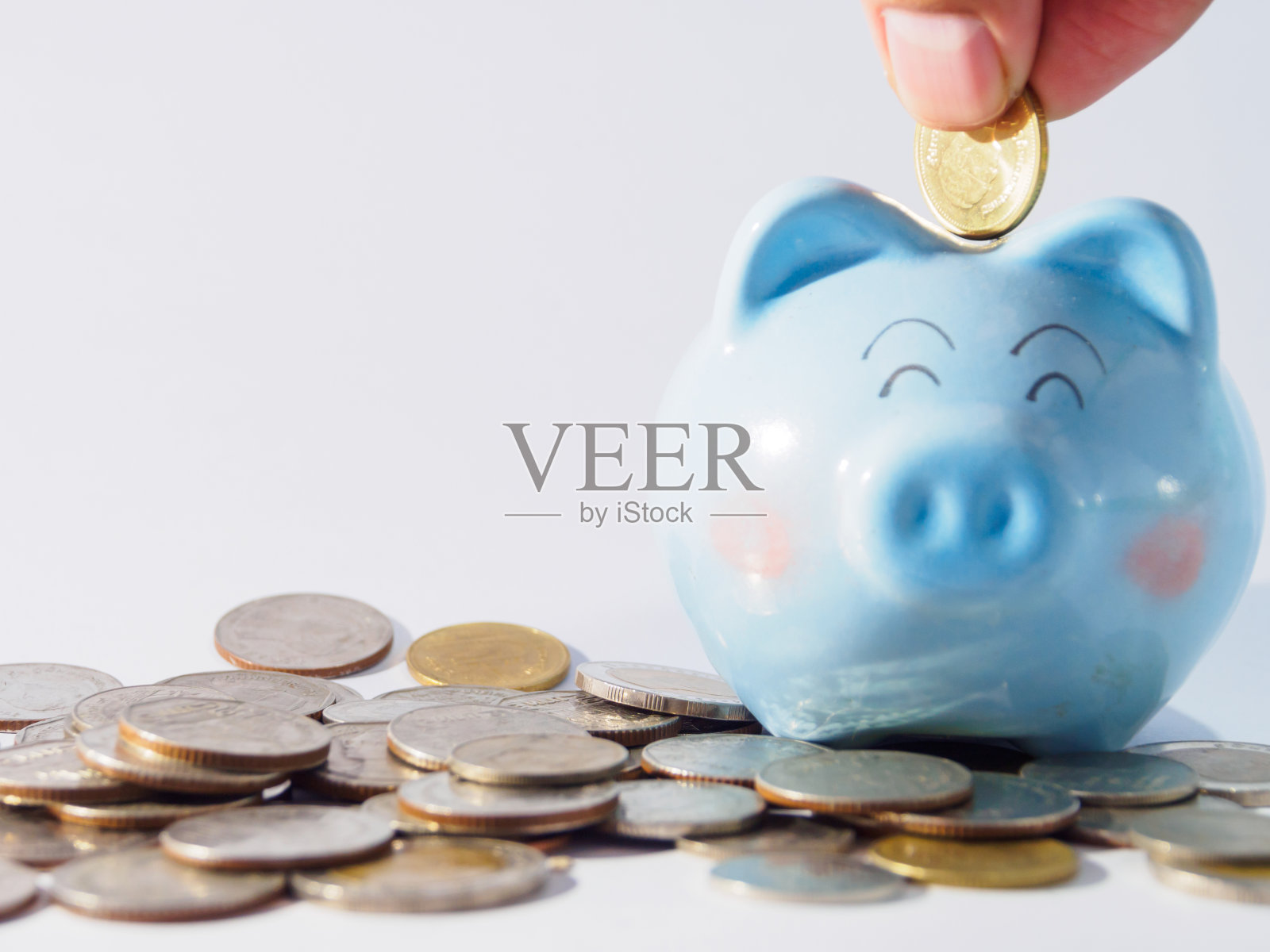 可爱的蓝色储蓄罐和手捡硬币掉在储蓄罐照片摄影图片