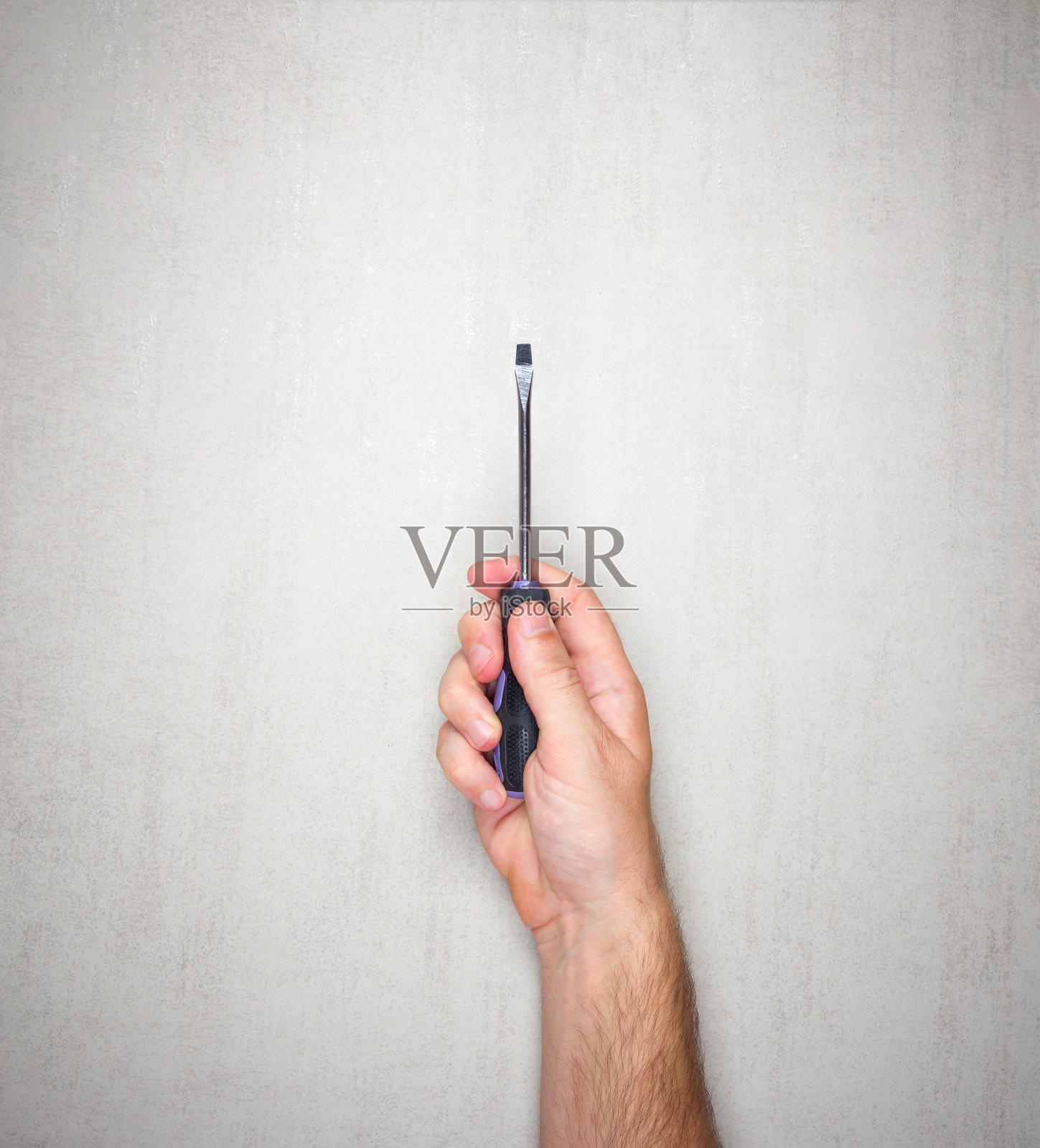 一个男人手中的螺丝刀,灰色背景,俯视图照片摄影图片