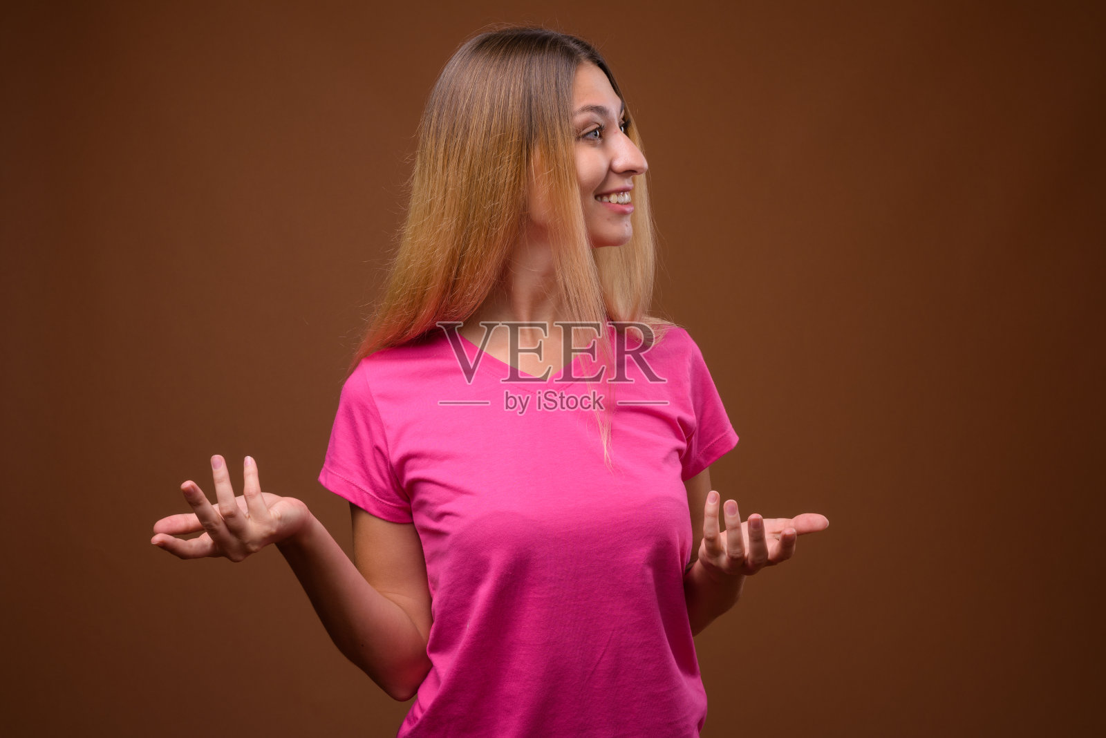 工作室拍摄的年轻美丽的女人穿着粉红色的衬衫,以彩色的背景照片摄影图片