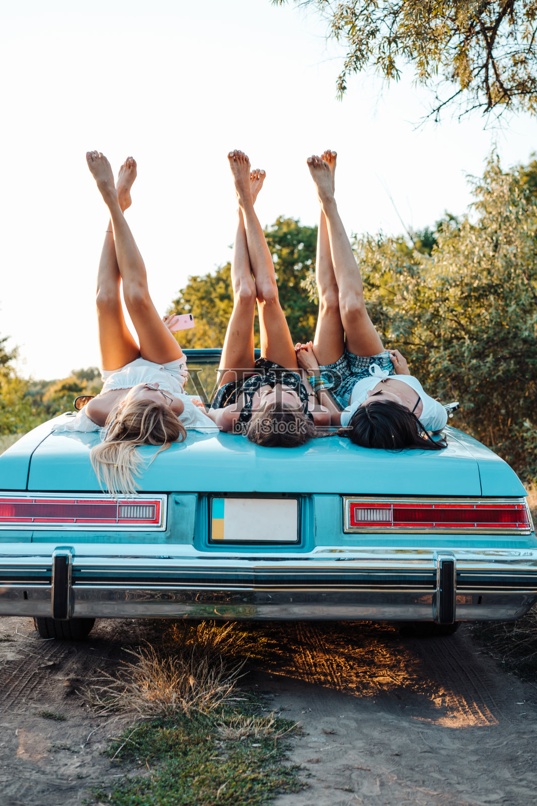 三个女孩躺在后备箱上照片摄影图片