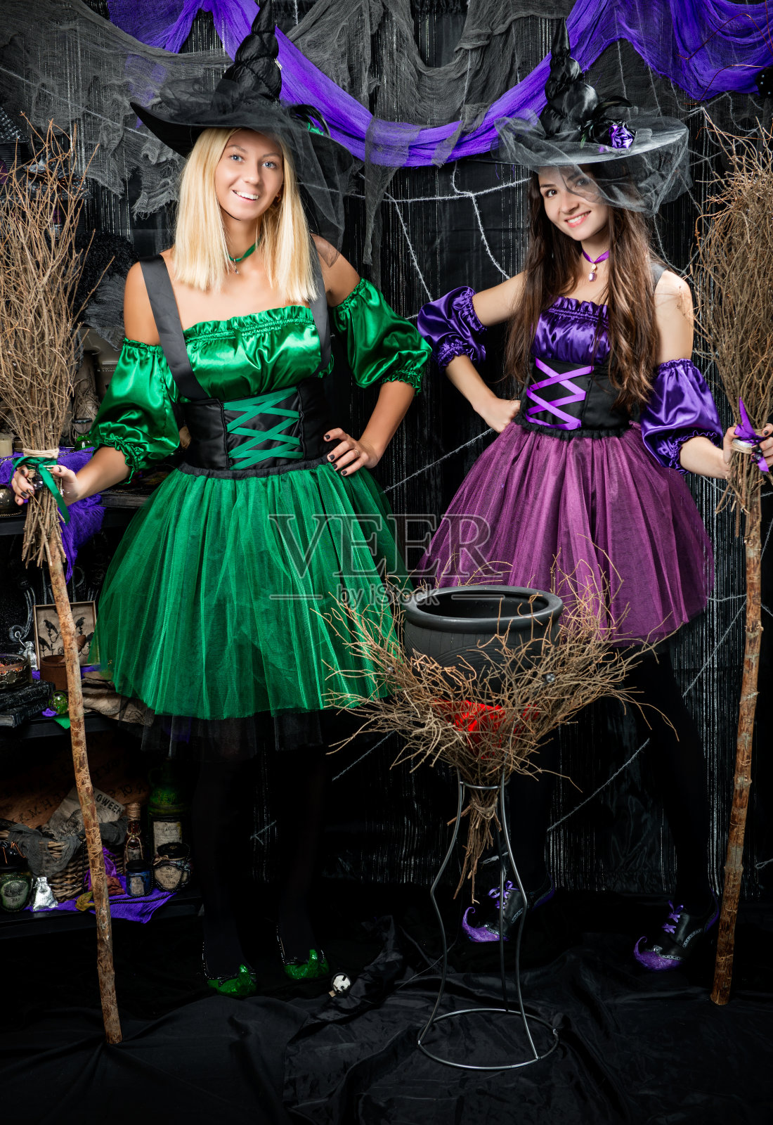 坩埚旁两个迷人的女巫的垂直肖像照片摄影图片