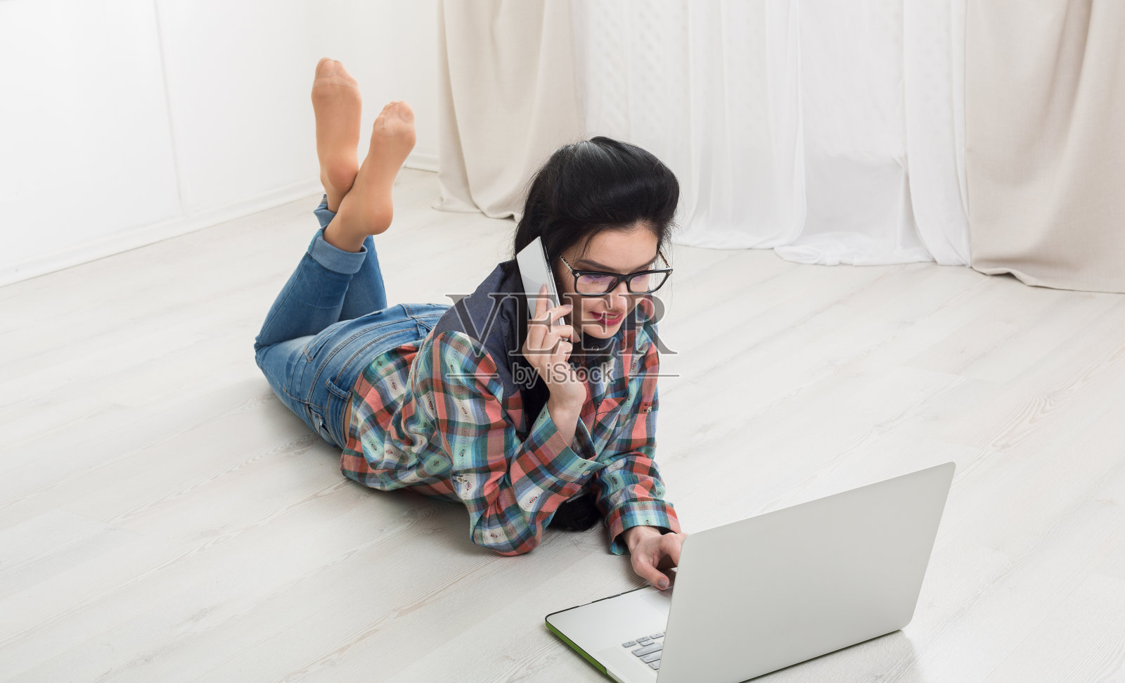 一个小女孩躺在笔记本电脑旁。照片摄影图片