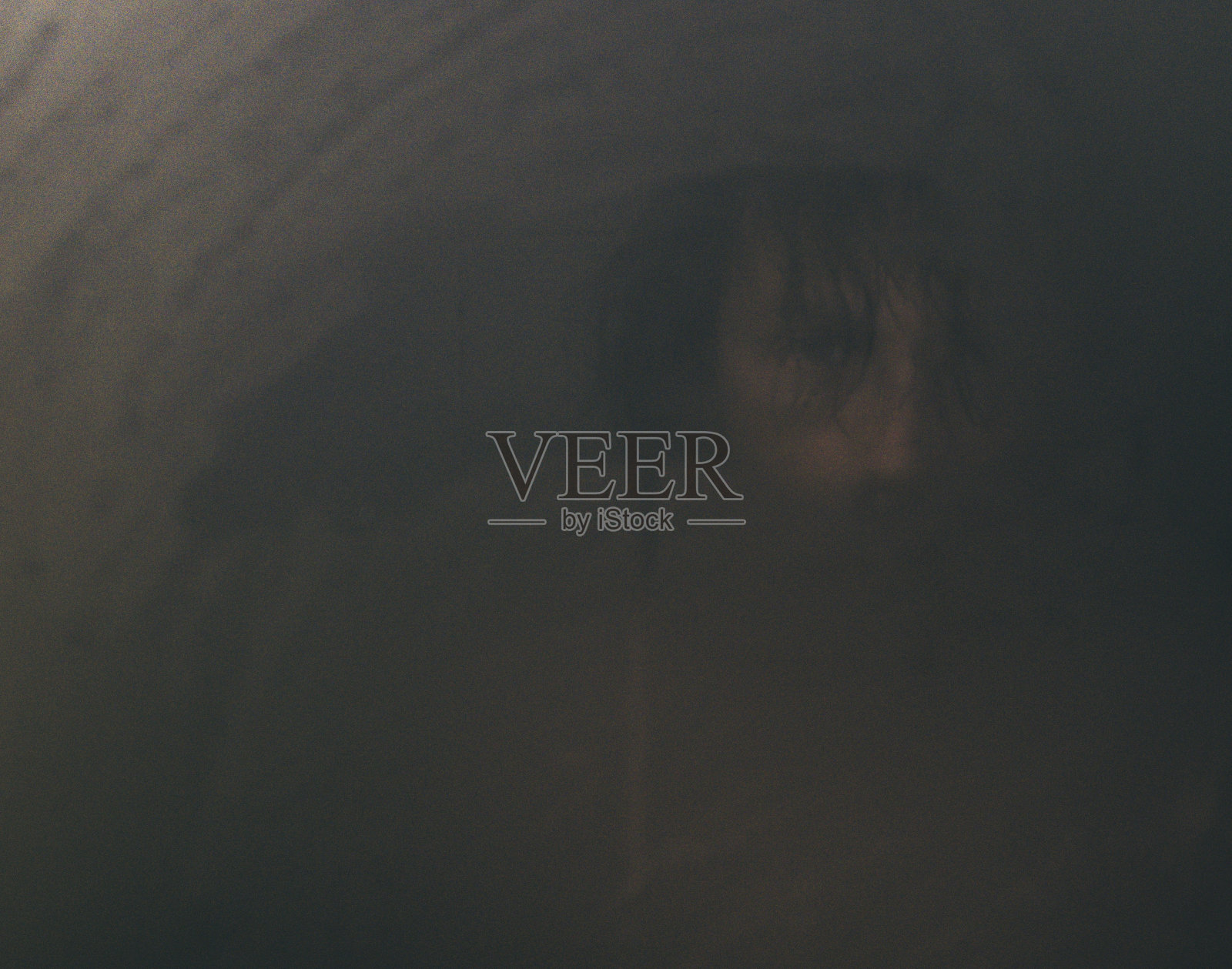 年轻人看着被蒸汽弄得模糊不清的镜子。照片摄影图片