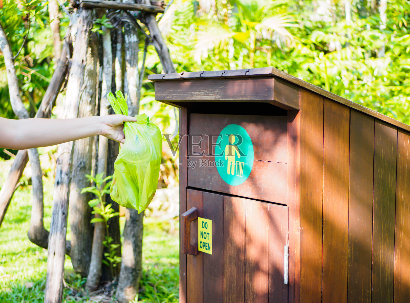 特写女子用手把塑料垃圾扔进垃圾桶。照片摄影图片