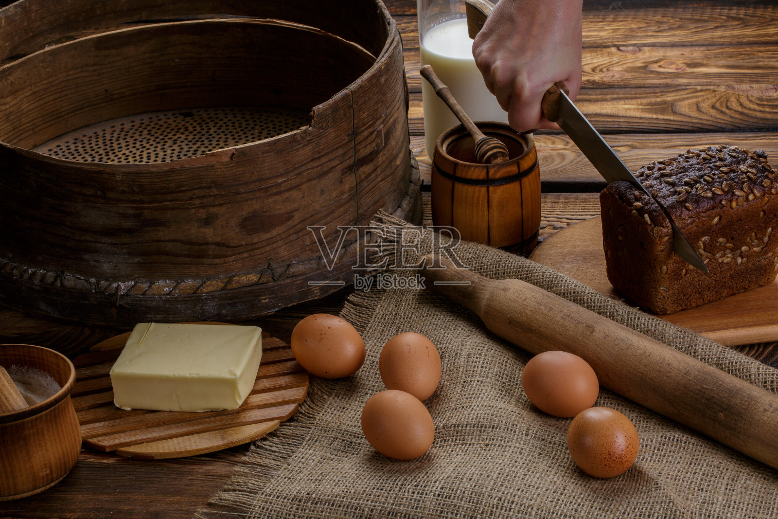 这只手在面包制作原料的背景上切黑面包照片摄影图片