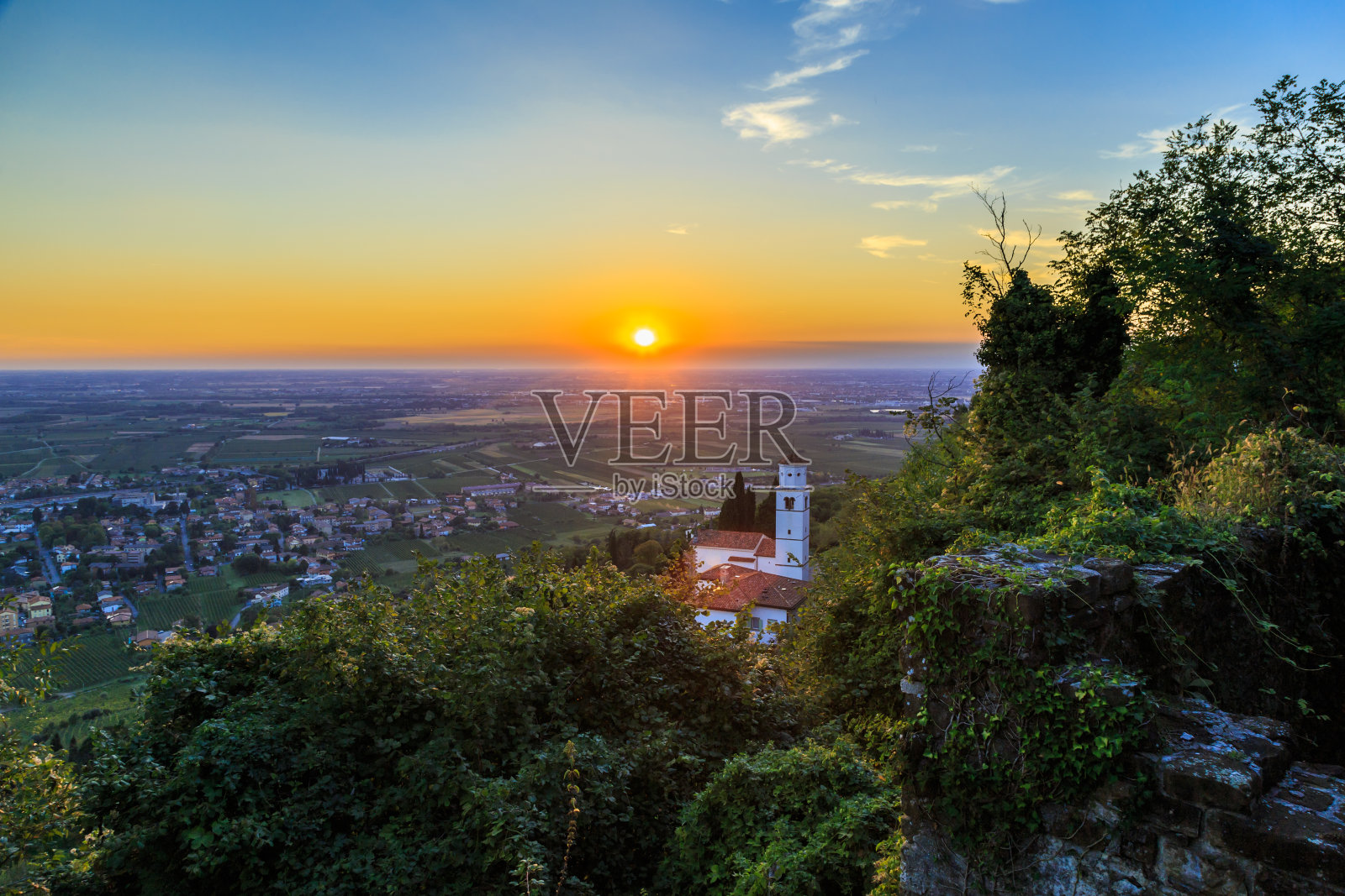 从山上看日落,教堂向下延伸到葡萄园照片摄影图片