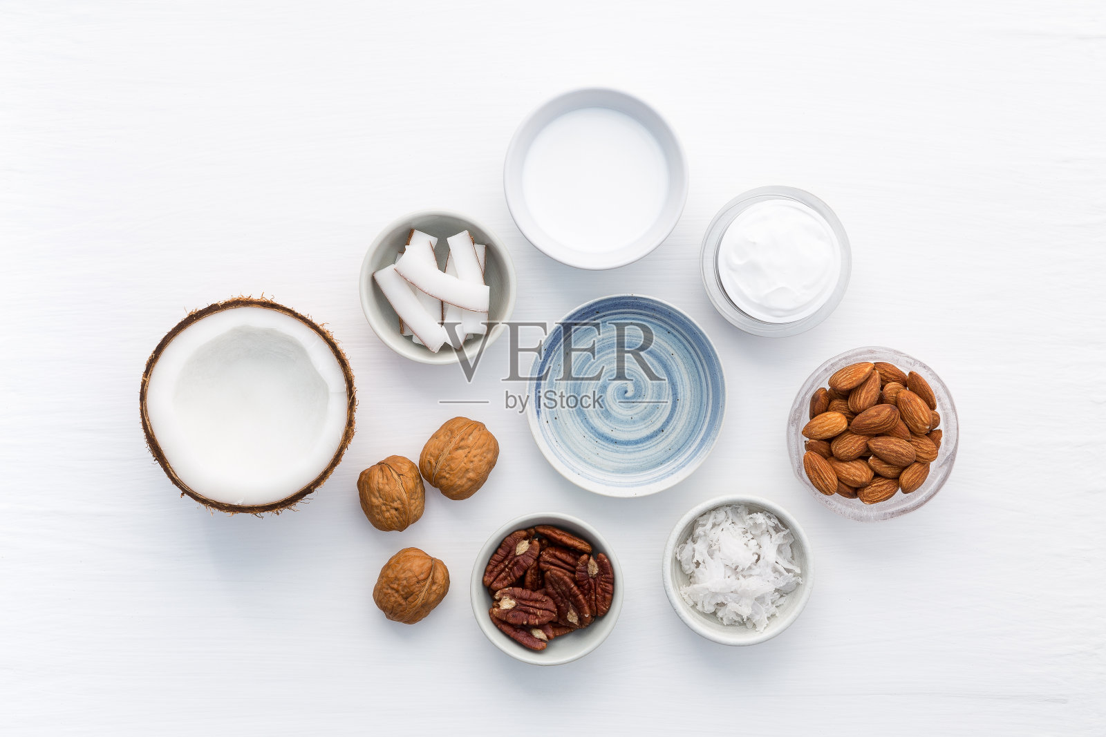 自制的护肤品放在白色的木制桌子上。从俯视图看,椰子,油,核桃,杏仁,磨砂,牛奶和乳液。适合空间和背景。照片摄影图片