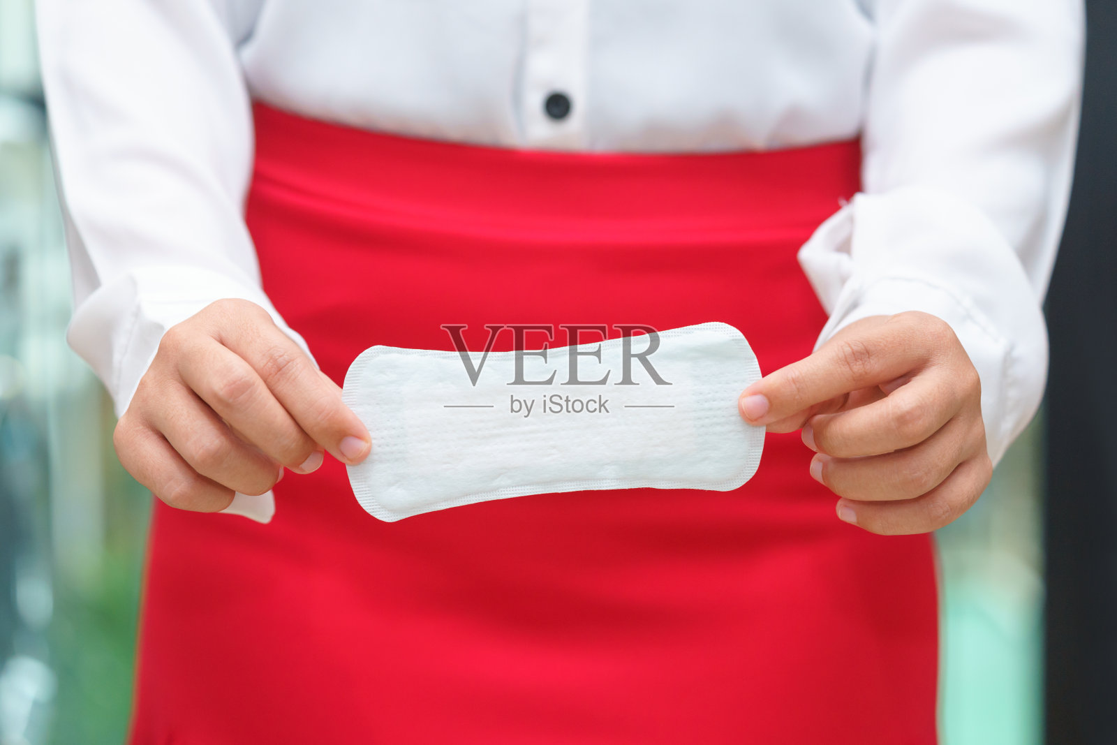 一个穿着红裙子拿着卫生巾的女人,一个月经来潮的女人。照片摄影图片