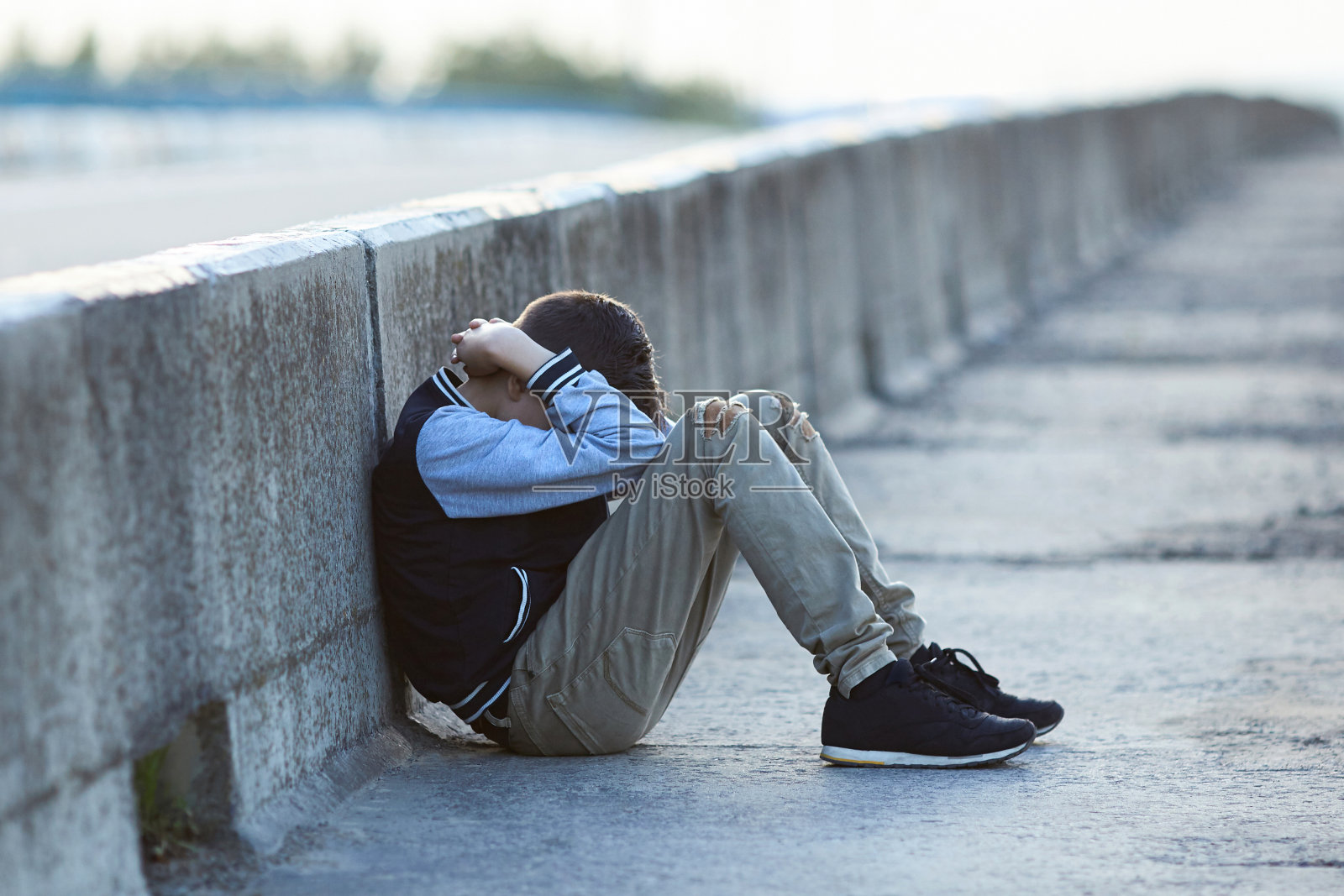 在桥上哭泣的年轻无家可归男孩照片摄影图片