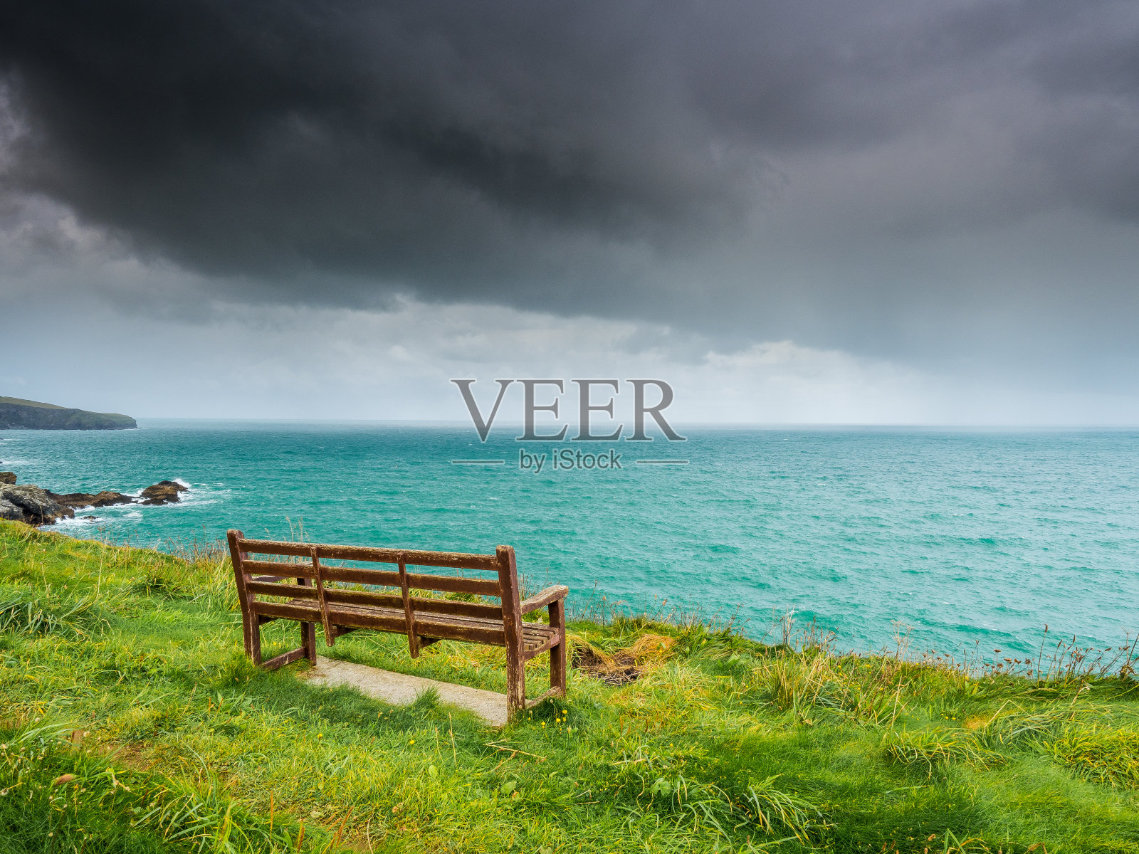 悬崖顶上的木凳上有暴风云照片摄影图片