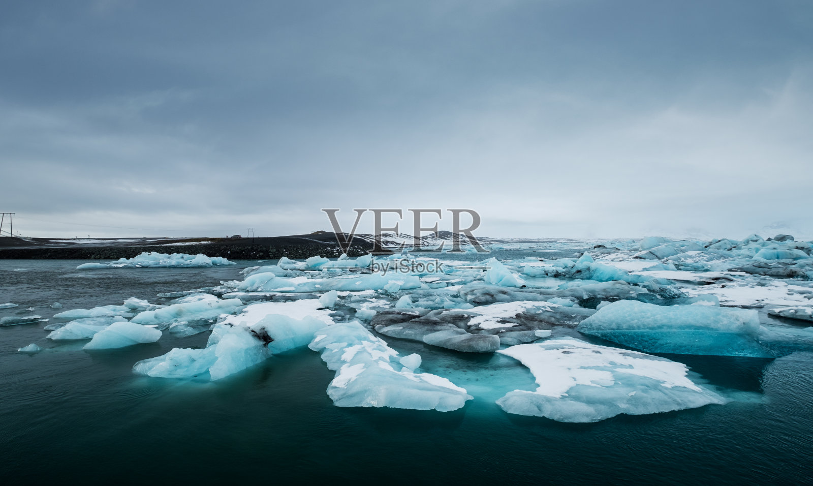 阴天,冰岛南部Jokulsarlon湖上的冰正在融化。全球变暖照片摄影图片