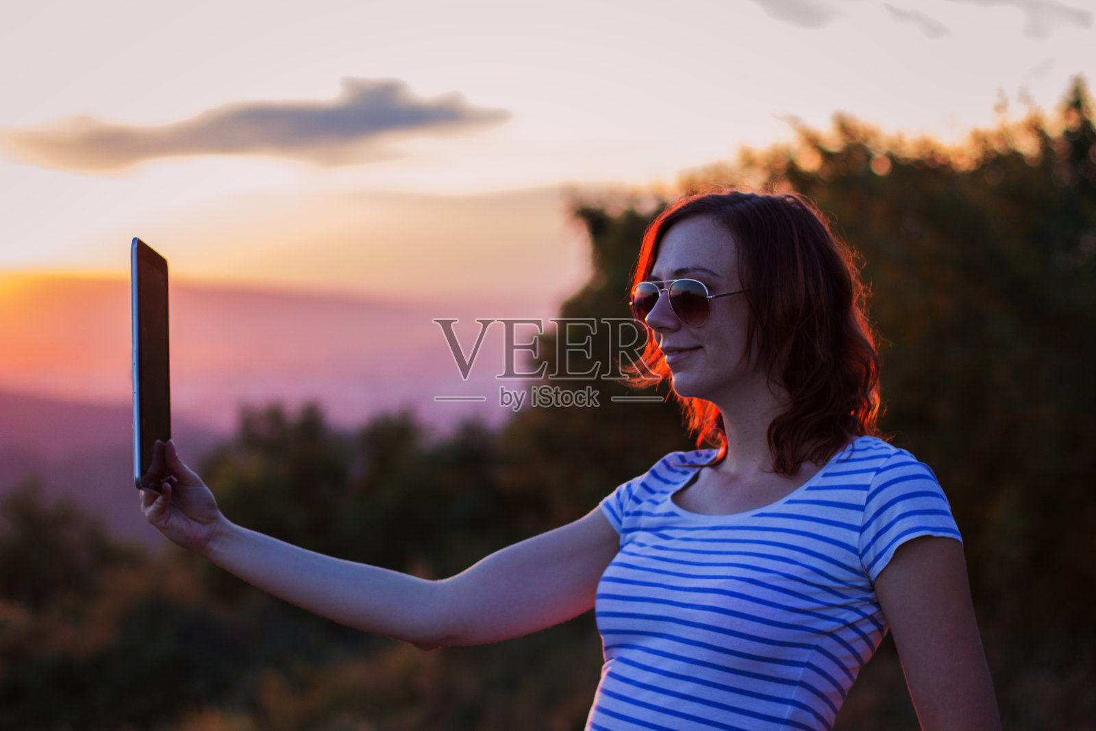 在夕阳下使用平板电脑的女人照片摄影图片