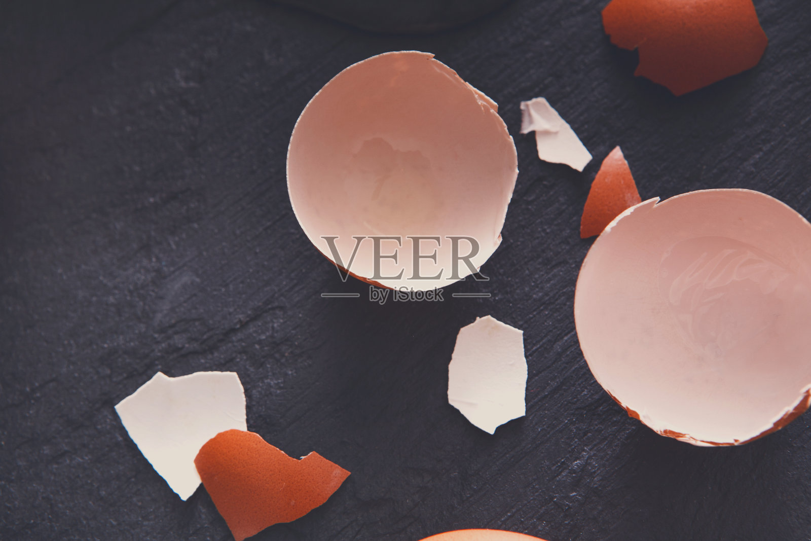 棕色有机有裂纹的鸡蛋,蛋黄在黑色背景上照片摄影图片