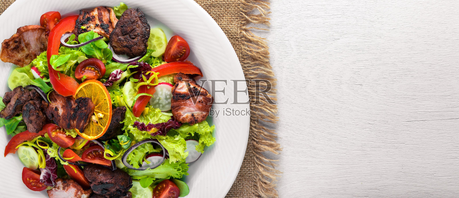 新鲜的黄瓜、西红柿和蔬菜沙拉,配上烤肉。前视图。自由空间。照片摄影图片