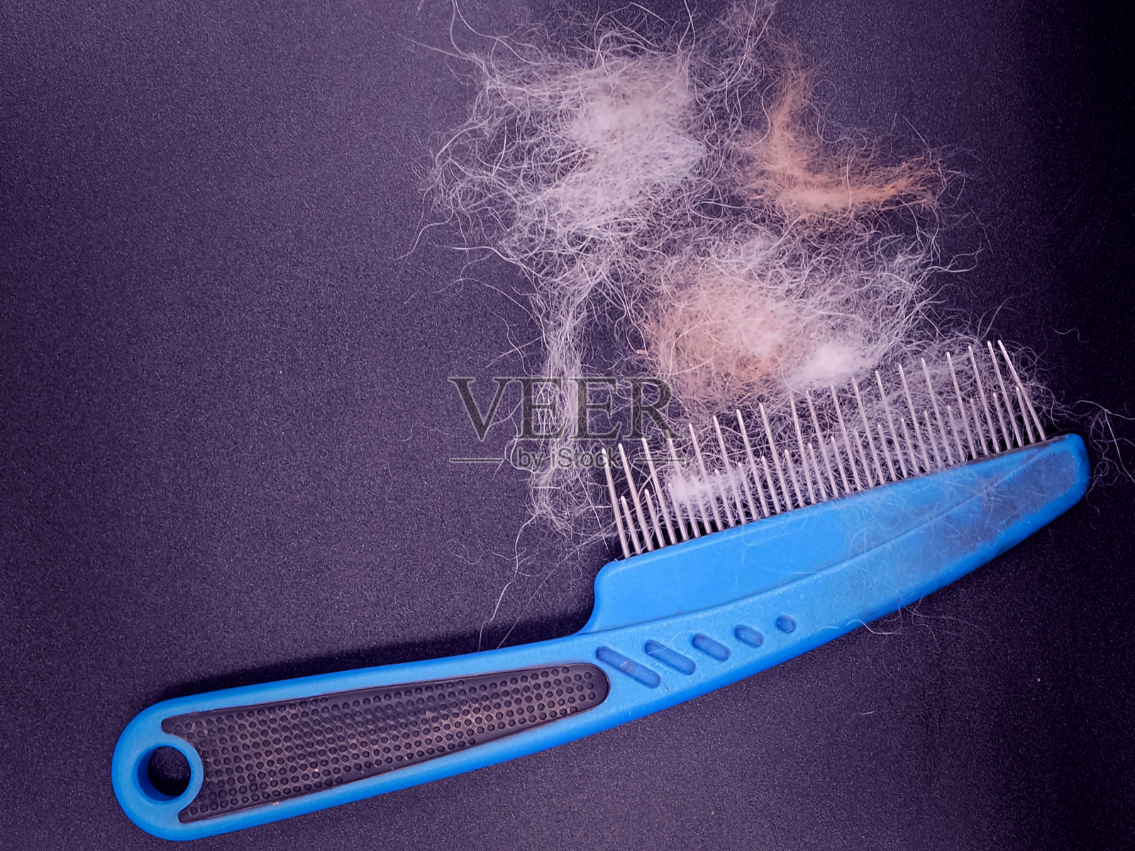 把狗毛和狗梳放在黑色的板子上,在右侧,以抽象的艺术设计,模糊的灯光环绕。照片摄影图片