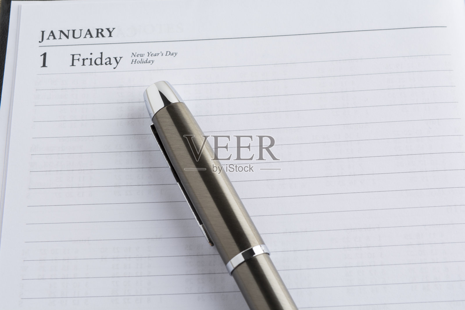 在日历上的金属笔上有一页,显示了一年的第一天在设定目标的概念照片摄影图片