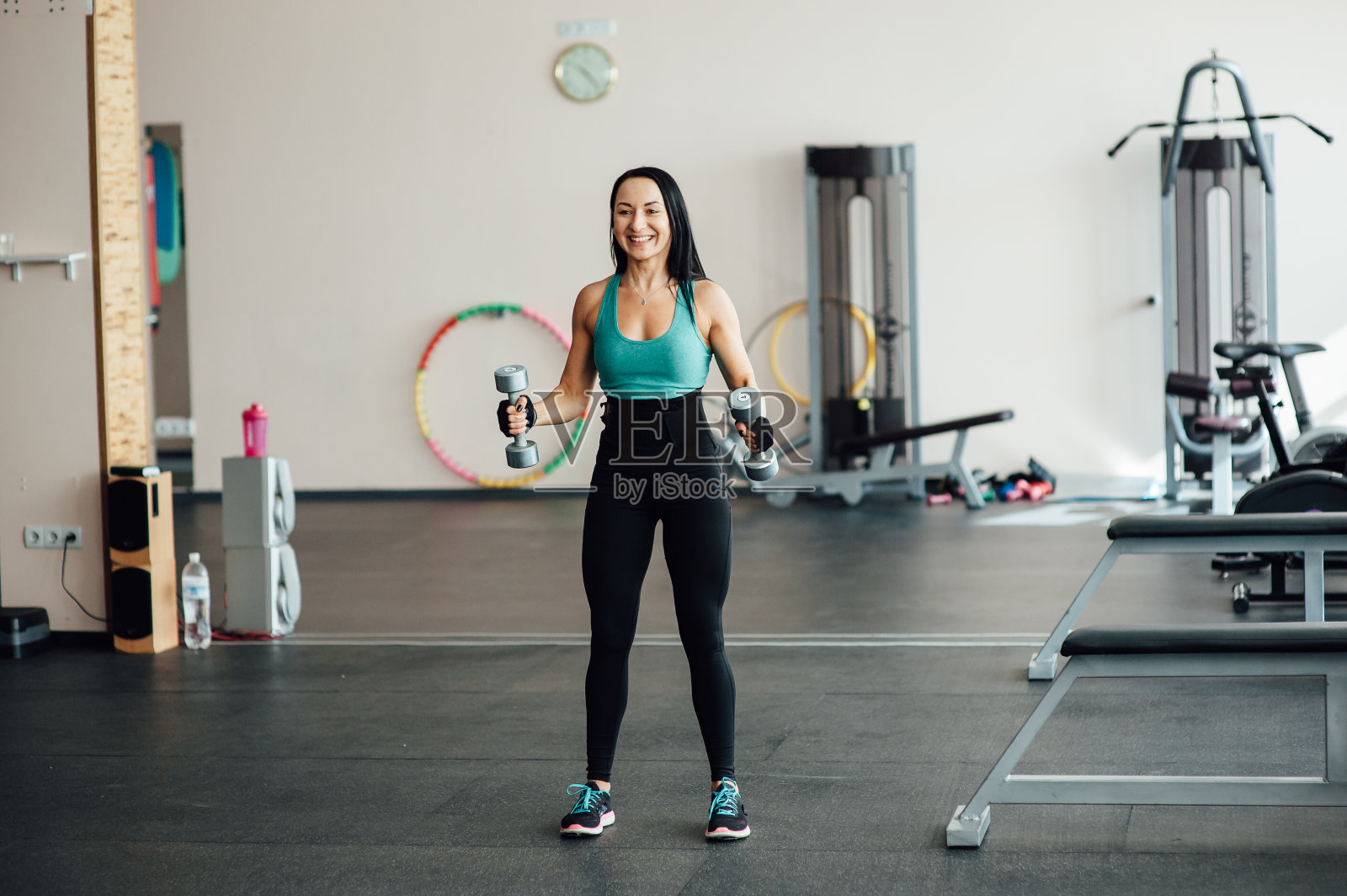 在健身房用哑铃锻炼的女人。照片摄影图片