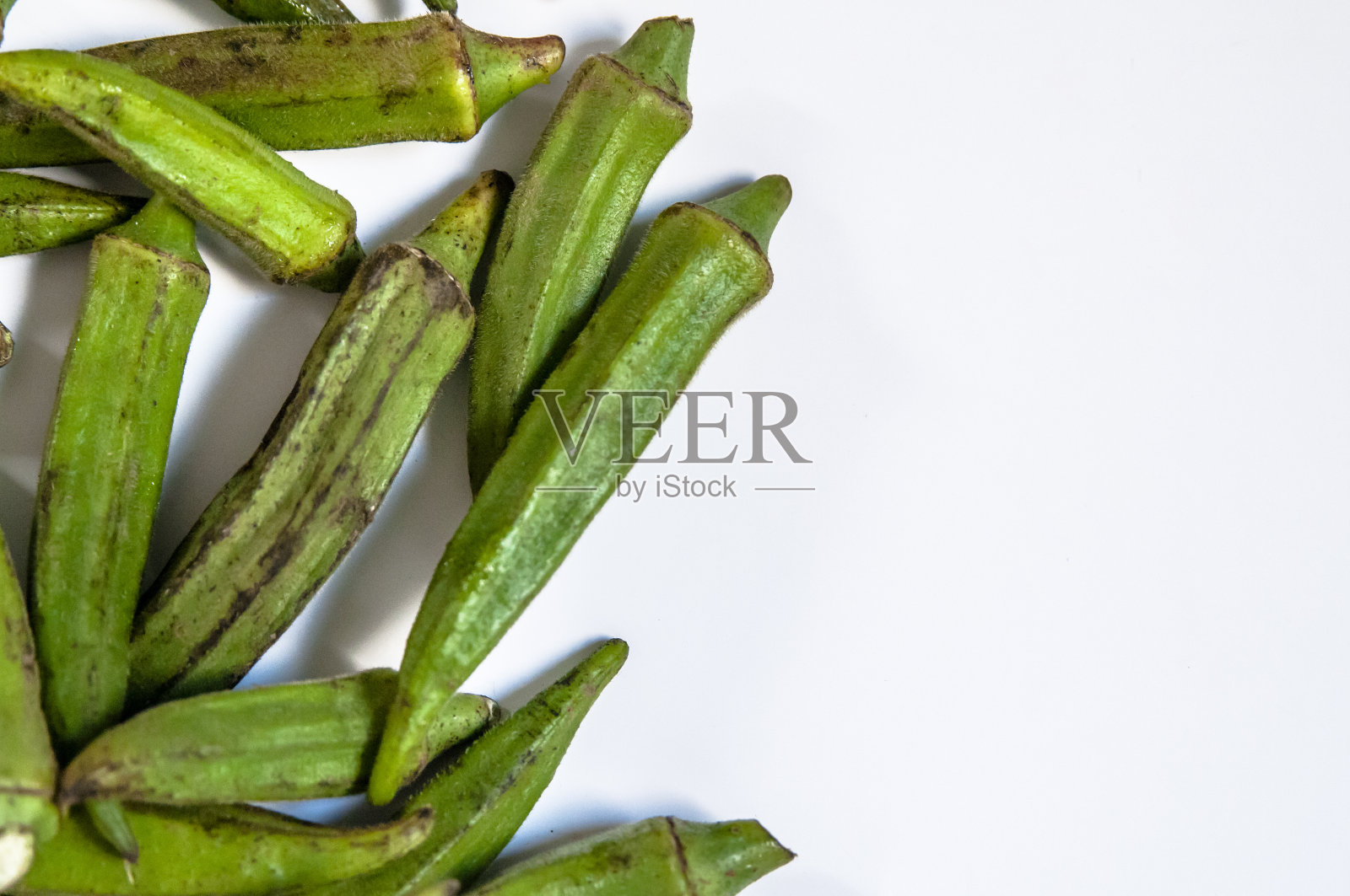 新鲜年轻的秋葵。白色背景上的绿色玫瑰。新鲜的秋葵。秋葵的堆栈。在白色背景上的黄秋葵高角度视图。白色的孤立的背景。空间的文本。照片摄影图片