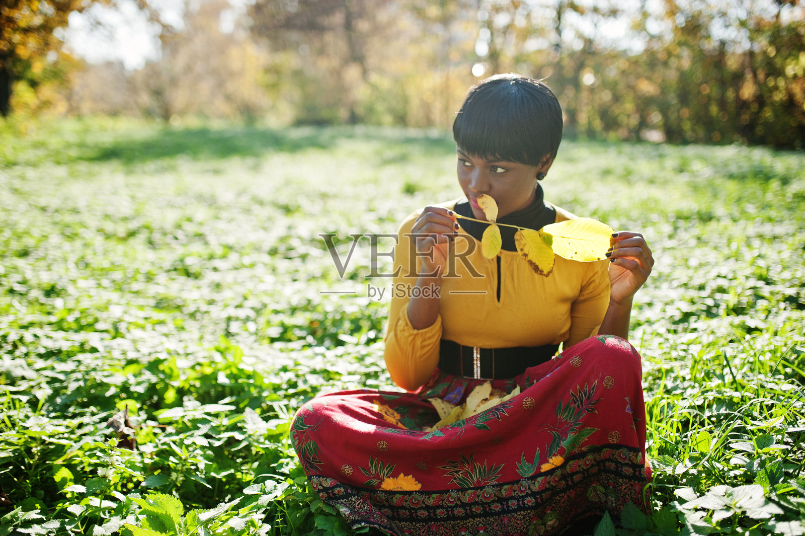 非裔美国女孩穿着黄色和红色的衣服在秋天秋天公园。照片摄影图片
