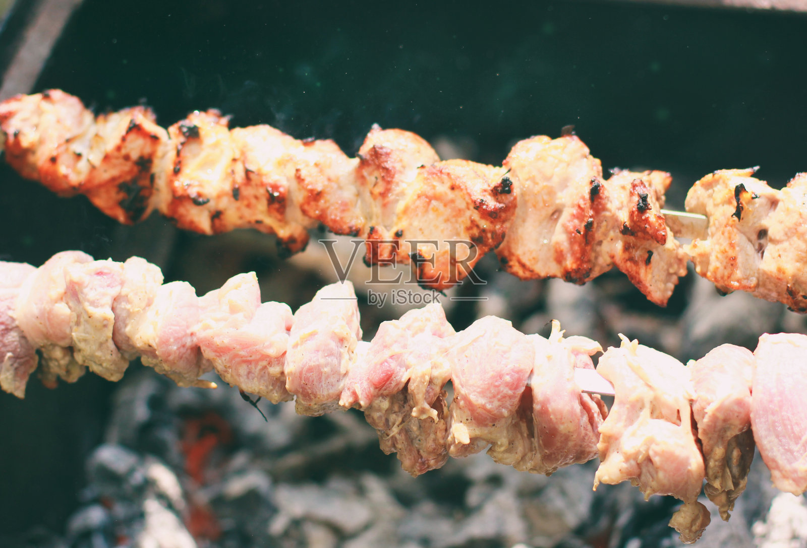 在金属串上烤烤肉。烤肉在烤肉上烤的肉烧烤用的是新鲜的猪肉切片。照片摄影图片