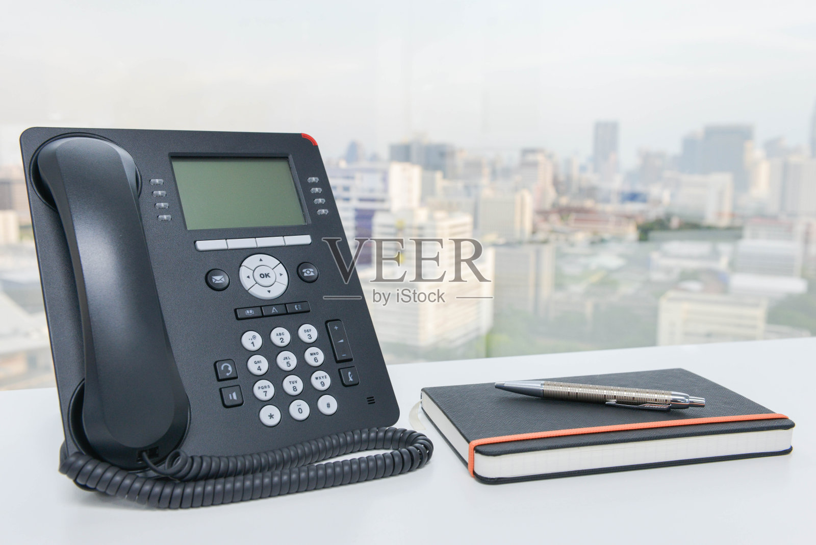 白色办公桌上放着IP电话和带笔笔记本照片摄影图片